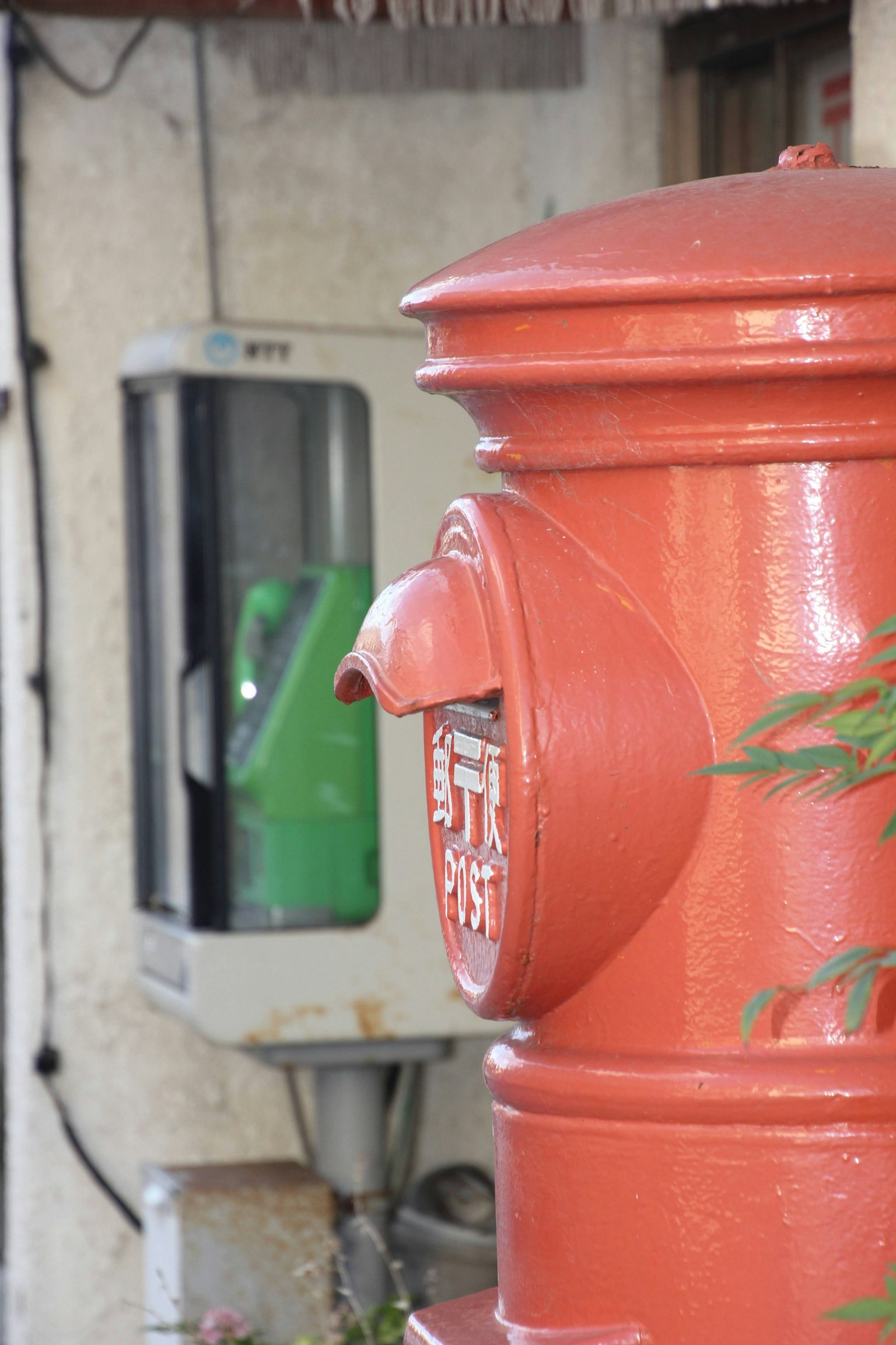 Boîte aux lettres rouge avec un téléphone public vert dans un paysage urbain