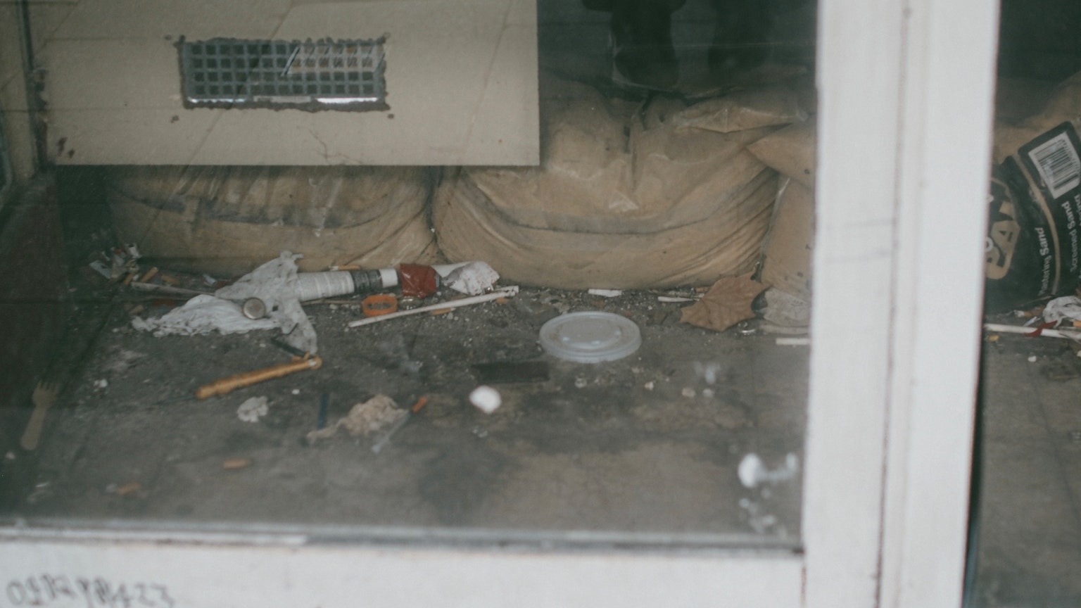 Una vista de un suelo sucio con basura esparcida vista a través de una ventana