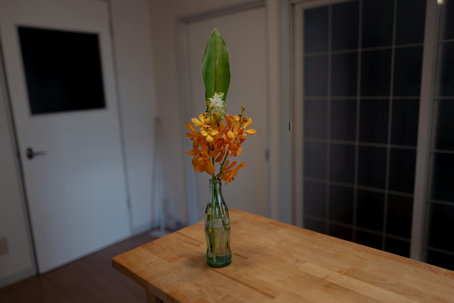 Eine ruhige Innenszene mit orangefarbenen Blumen und grünen Blättern in einer Vase