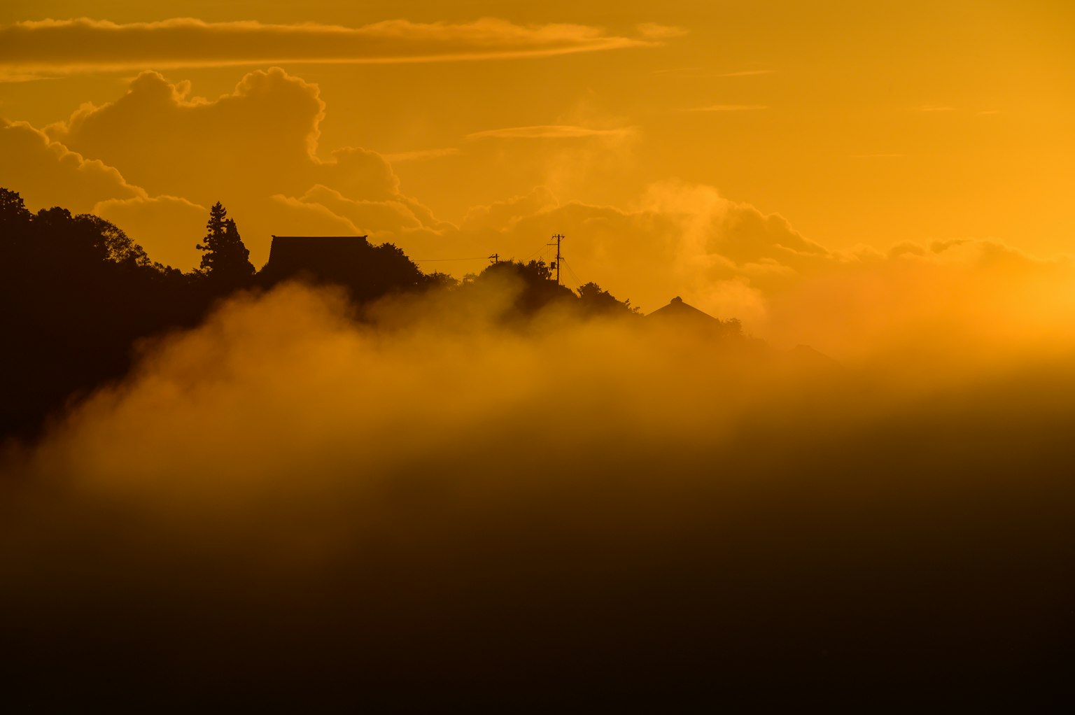 Silhouette de montagnes enveloppées de brume au coucher du soleil