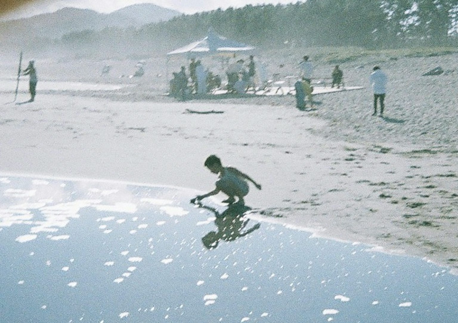 Enfant jouant sur la plage avec reflet dans l'eau