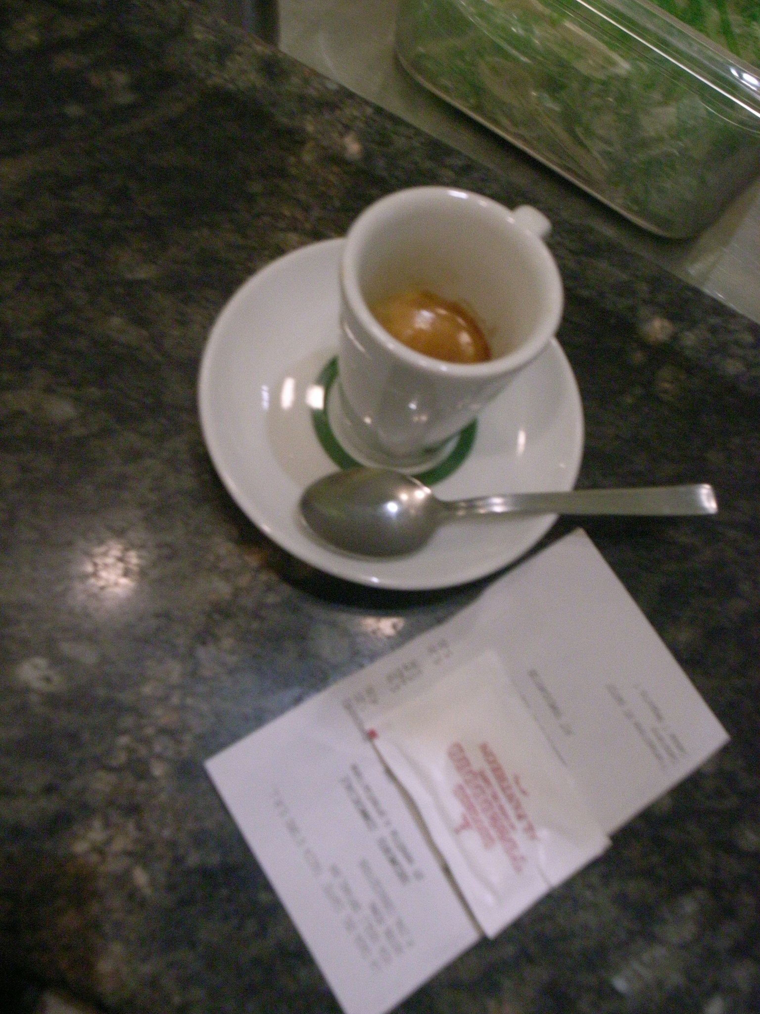 Taza de espresso con cuchara y recibos sobre una mesa