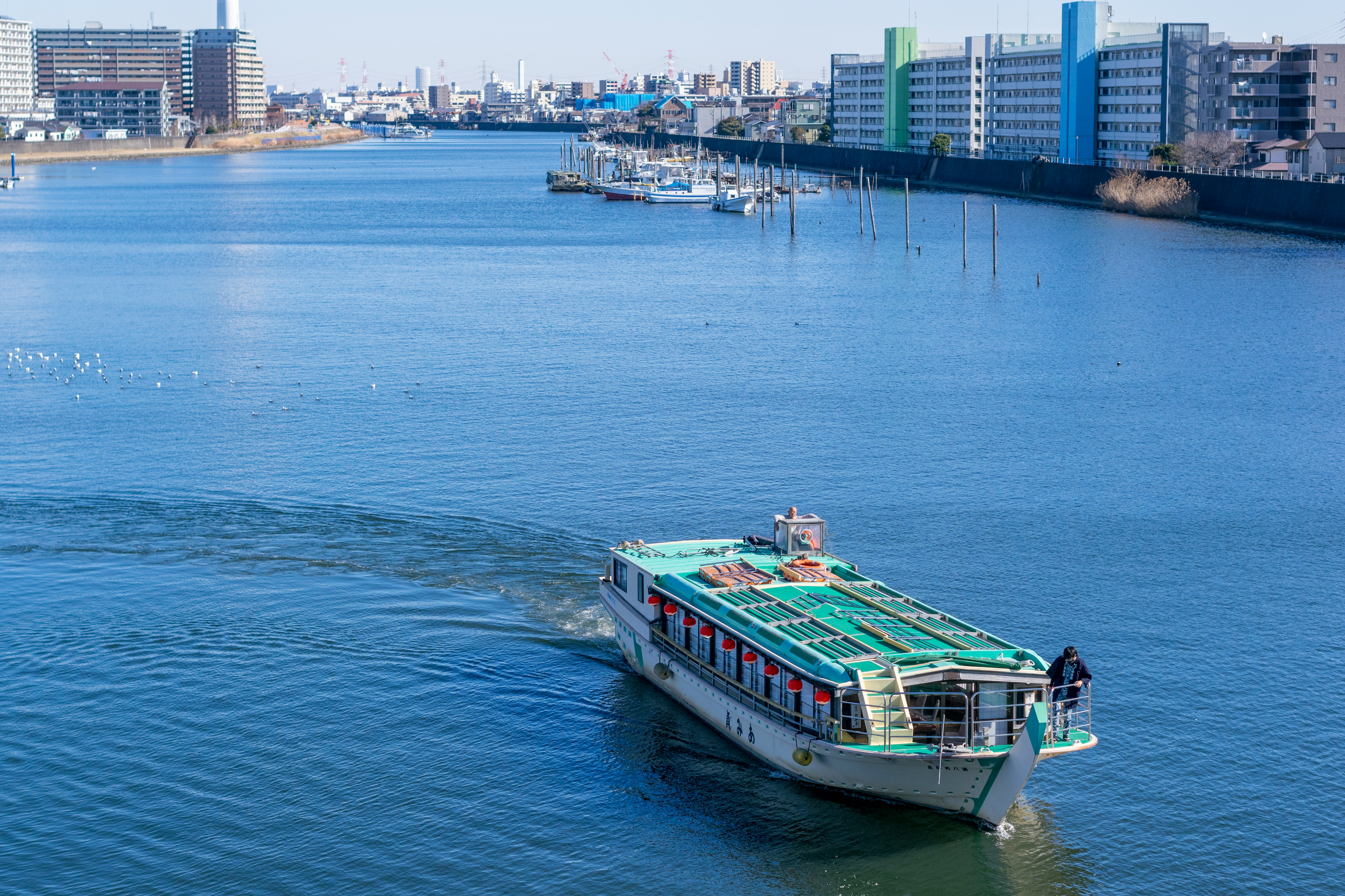Large cargo ship sailing along a river near a harbor