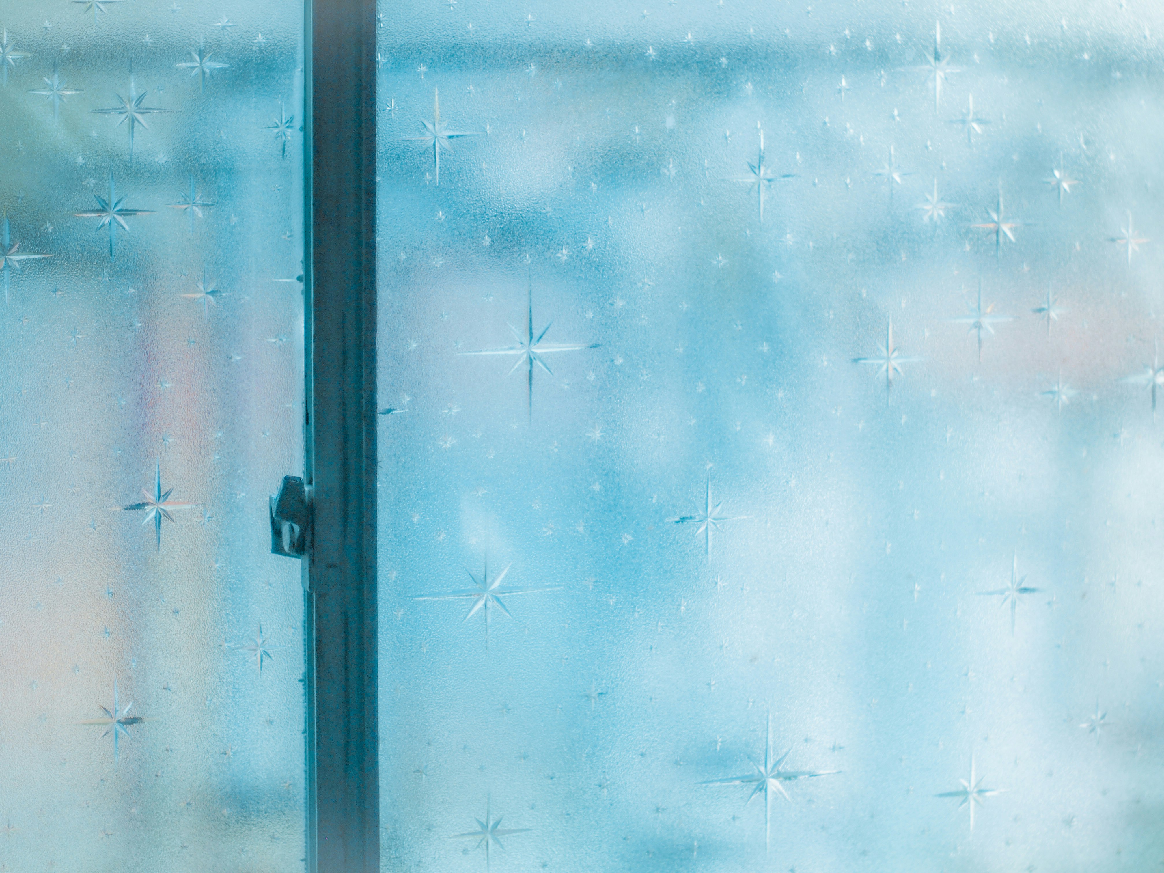 窓ガラス越しに舞う雪と青い光の粒