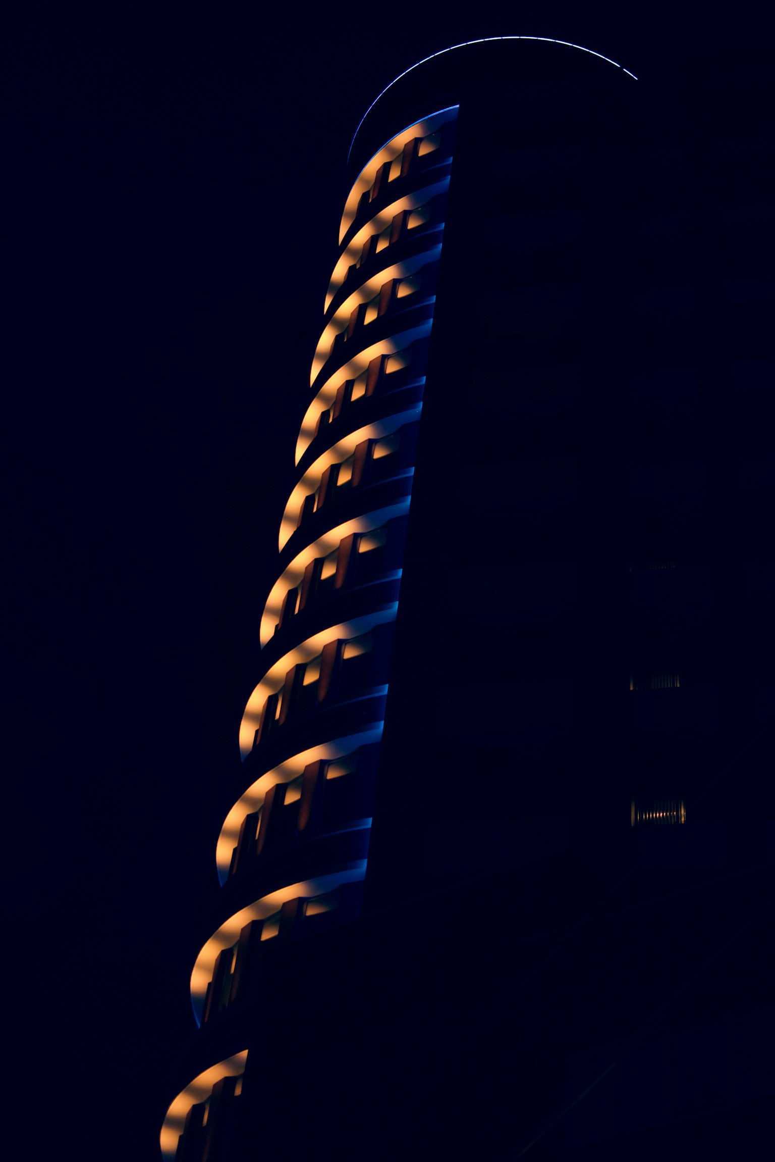 Una sección de un edificio en espiral iluminado contra un fondo oscuro