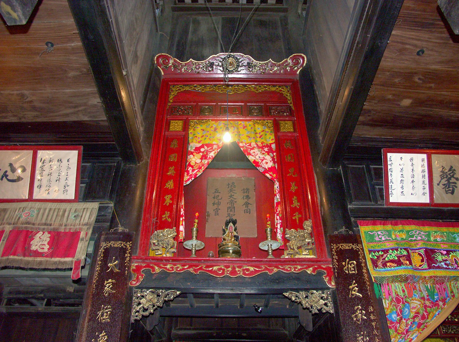 Interior of a room featuring a red decorative altar and traditional Chinese calligraphy