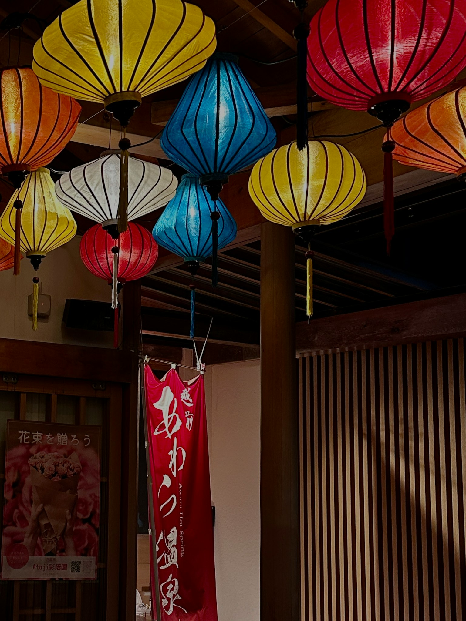 Lampion berwarna-warni tergantung di dalam ruangan spanduk merah yang mencolok