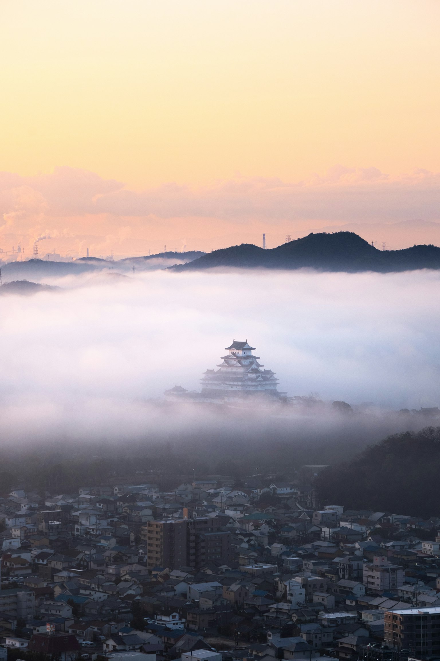 Himeji Castle surrounded by fog with a cityscape in the foreground