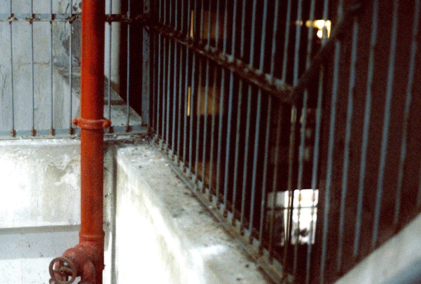narrow alley passage with red railings and pipes along the wall