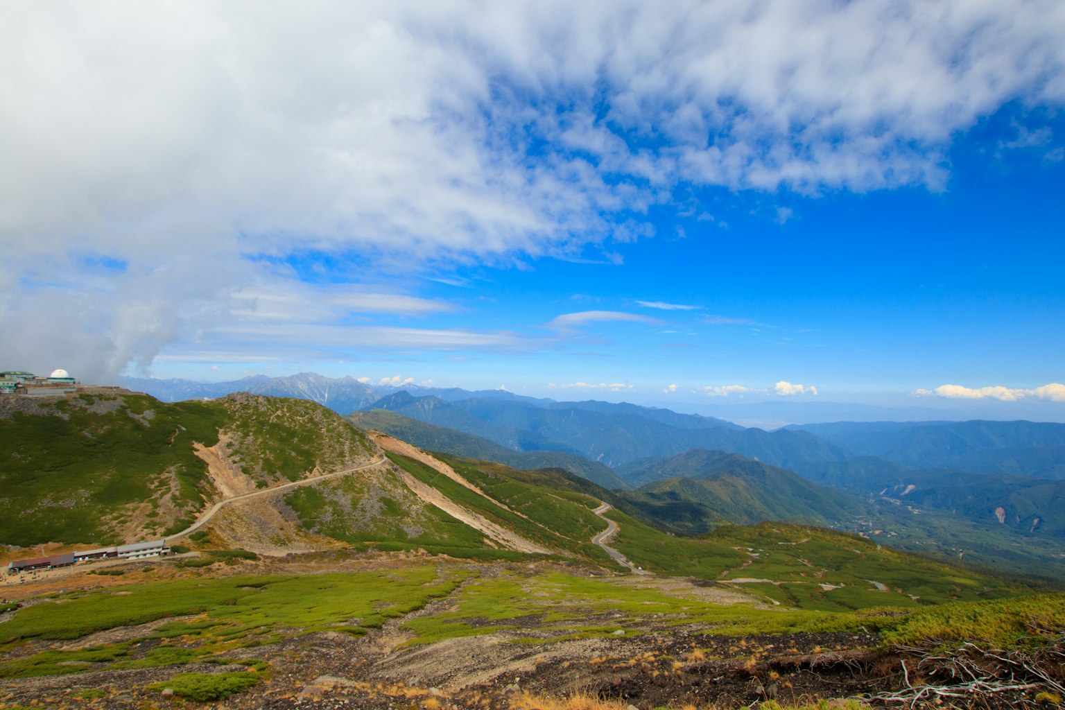 蓝天和云朵环绕的山景 绿色草地和可见的道路