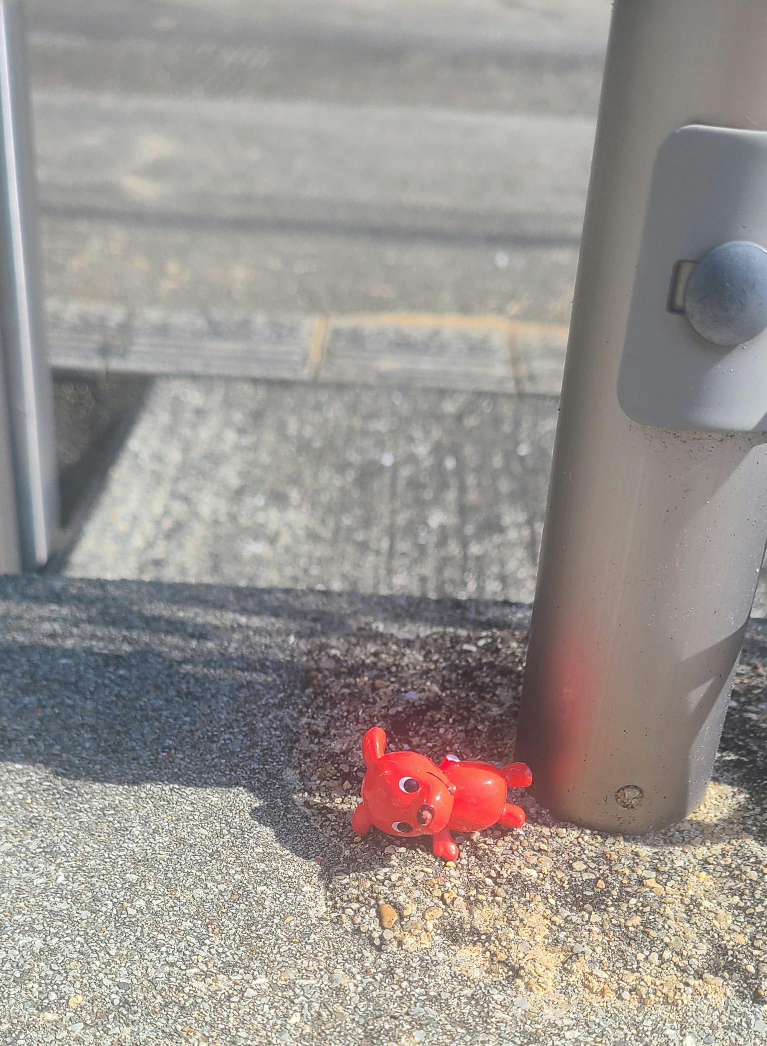 Ein kleines rotes Plastikspielzeug neben einem Metallpfosten