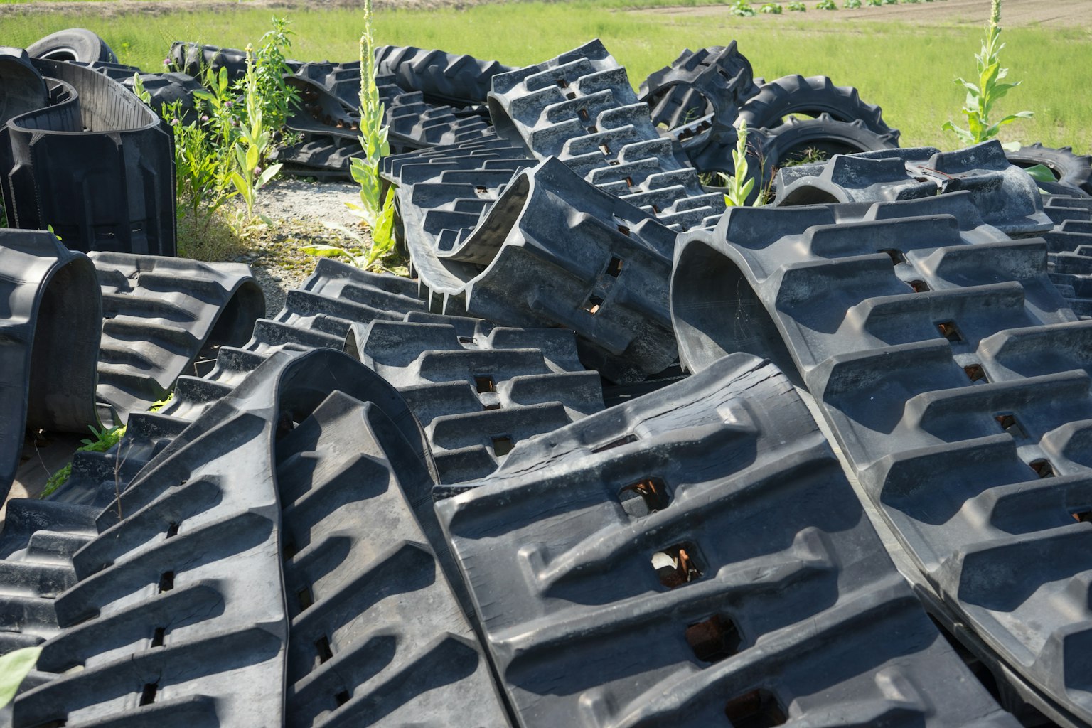 Un paysage de plaques de chenille noires empilées dans une zone herbeuse