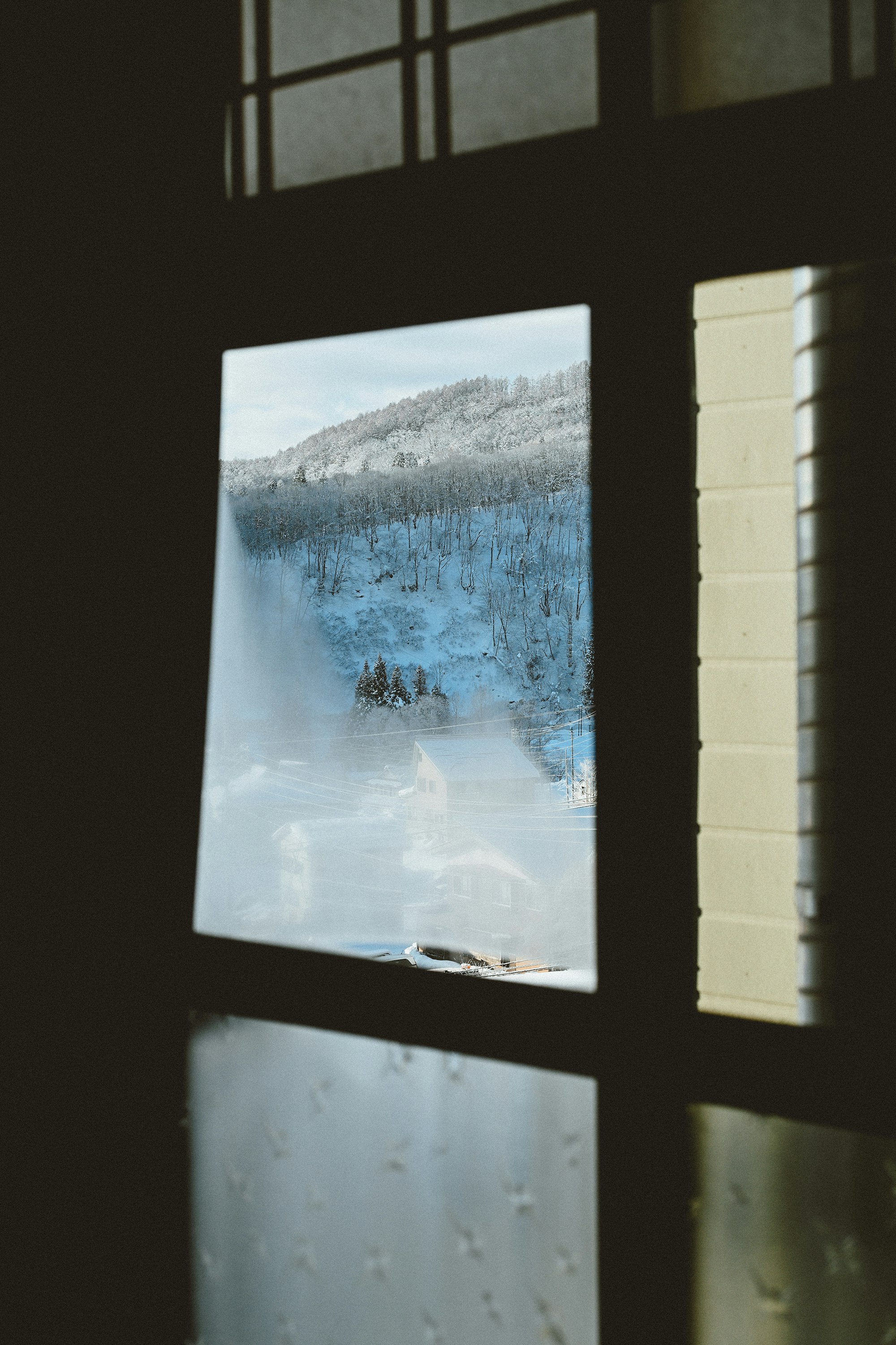 窓の格子越しに見える雪景色の写真