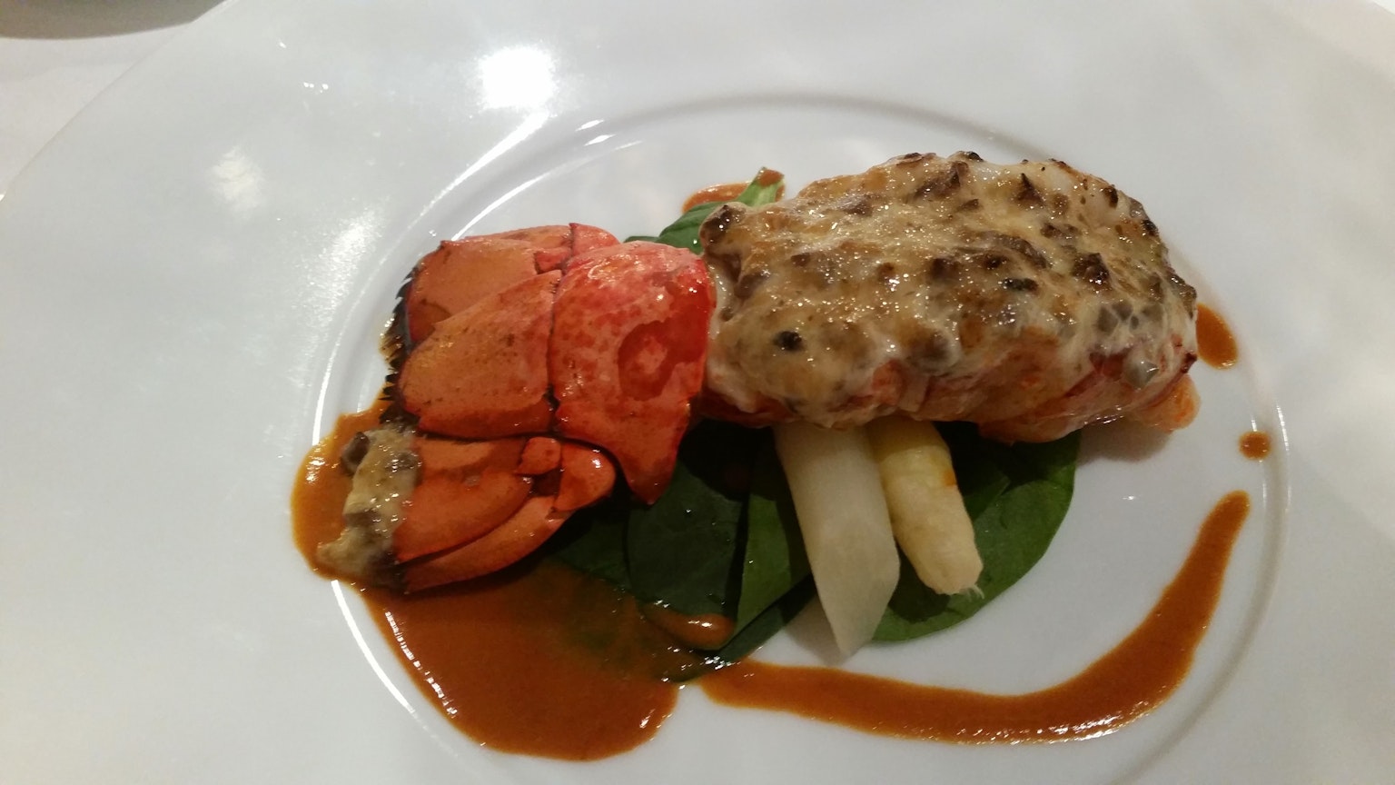 Gourmetgericht auf dem Teller mit Lachs weißen Spargel Spinat und Sauce