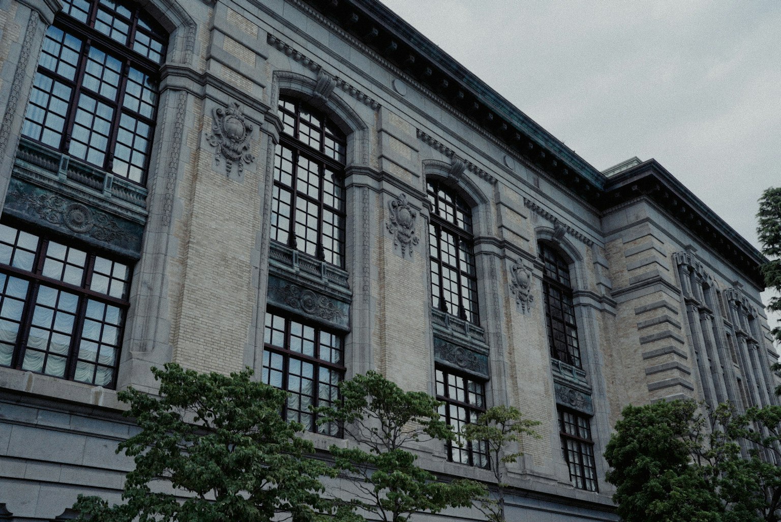 Historic building exterior with decorative windows and green plants