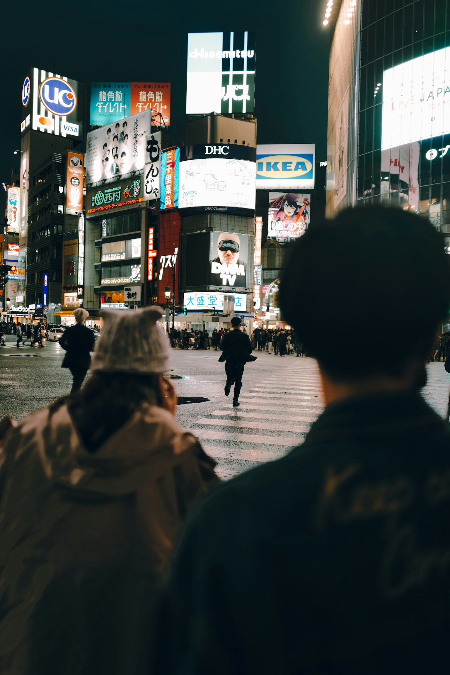 Personas cruzando la calle en una ciudad vibrante por la noche con letreros brillantes