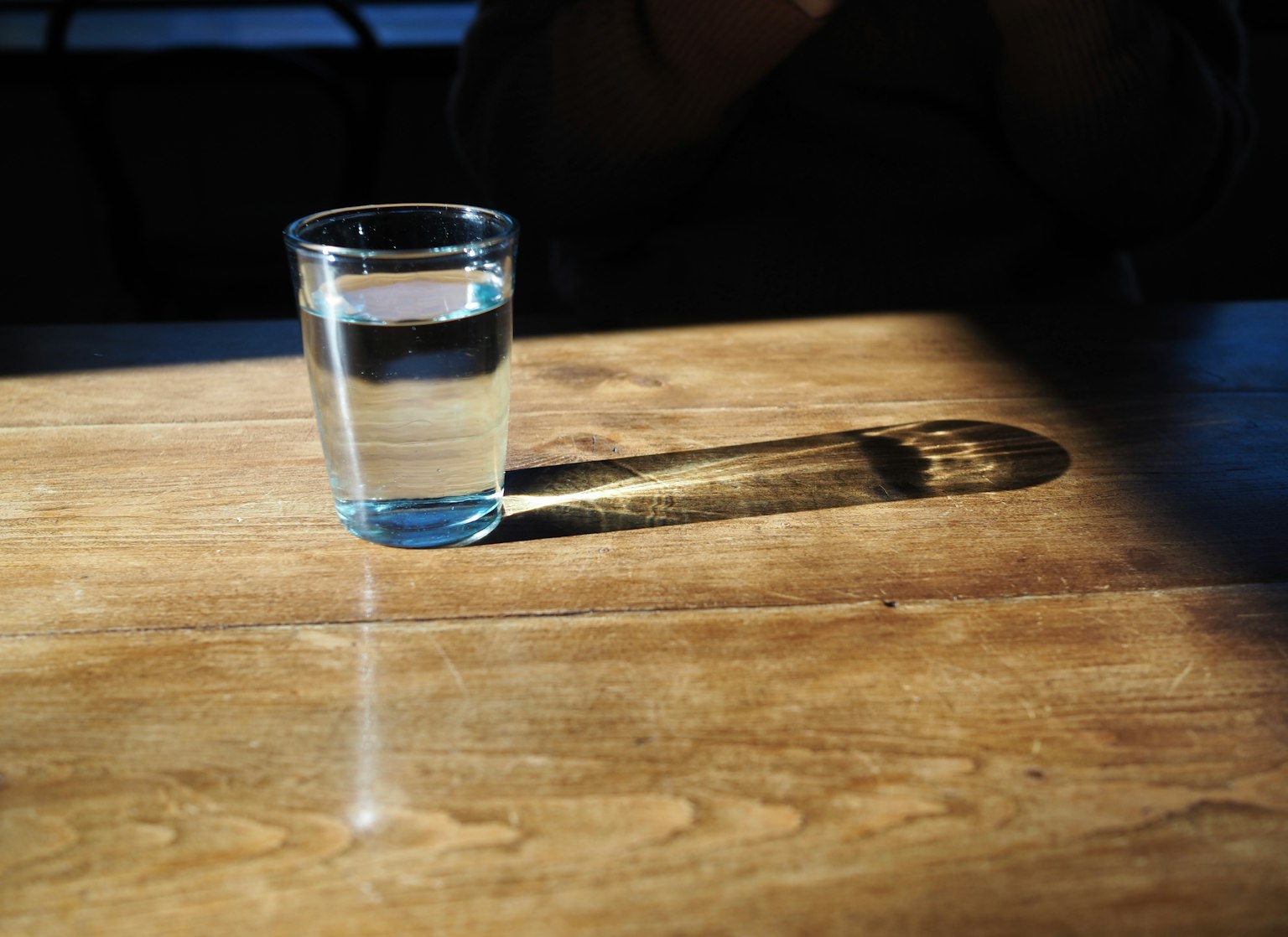 一杯水在木桌上投射阴影