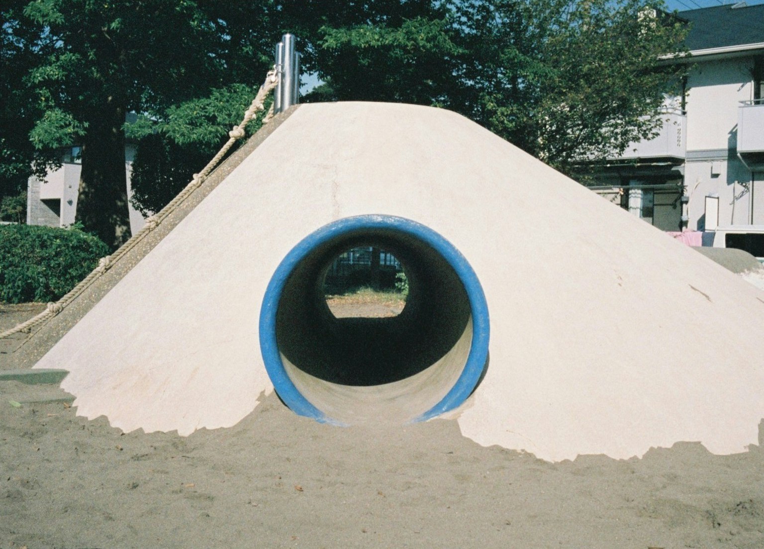 Playground feature with a blue tunnel on a sand hill