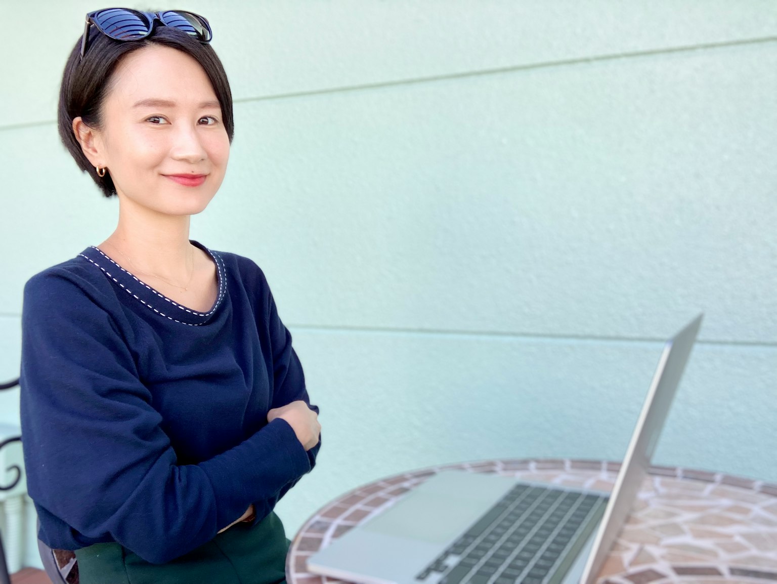 Eine Frau in lässiger Kleidung lächelt vor einem Laptop