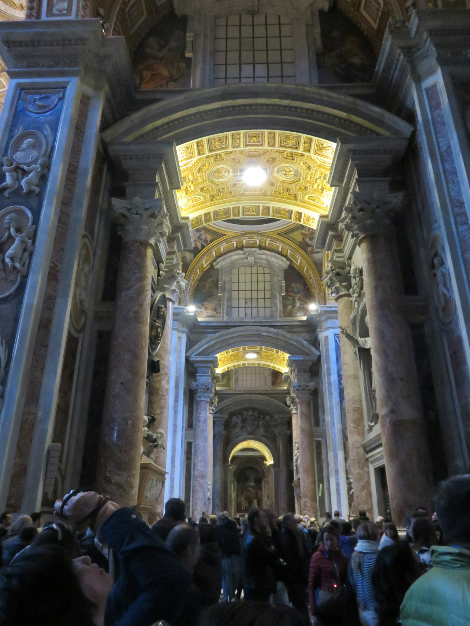 Interior de la Basílica de San Pedro con arquitectura grandiosa y multitudes de visitantes