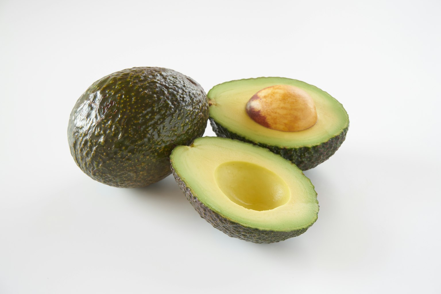Avocats entier et coupé en deux sur un fond blanc