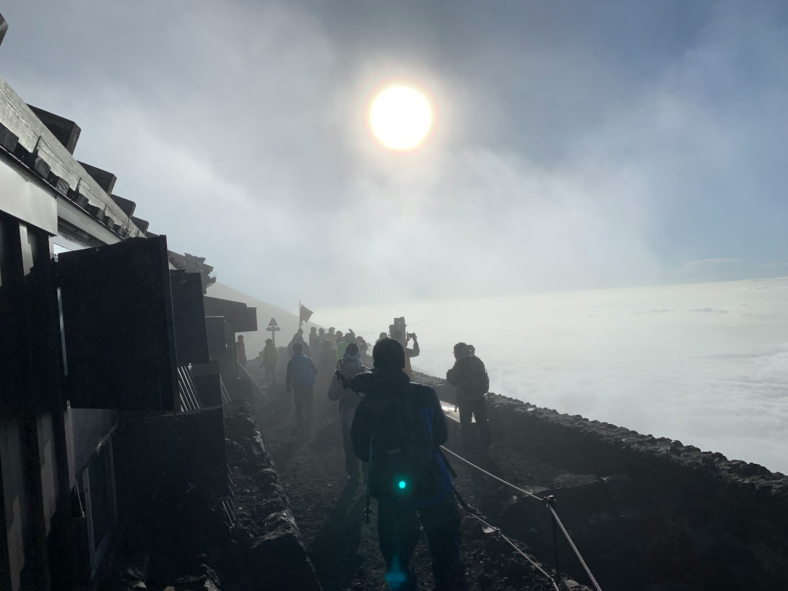 登山者在霧中攀登山峰，陽光透過雲層照耀