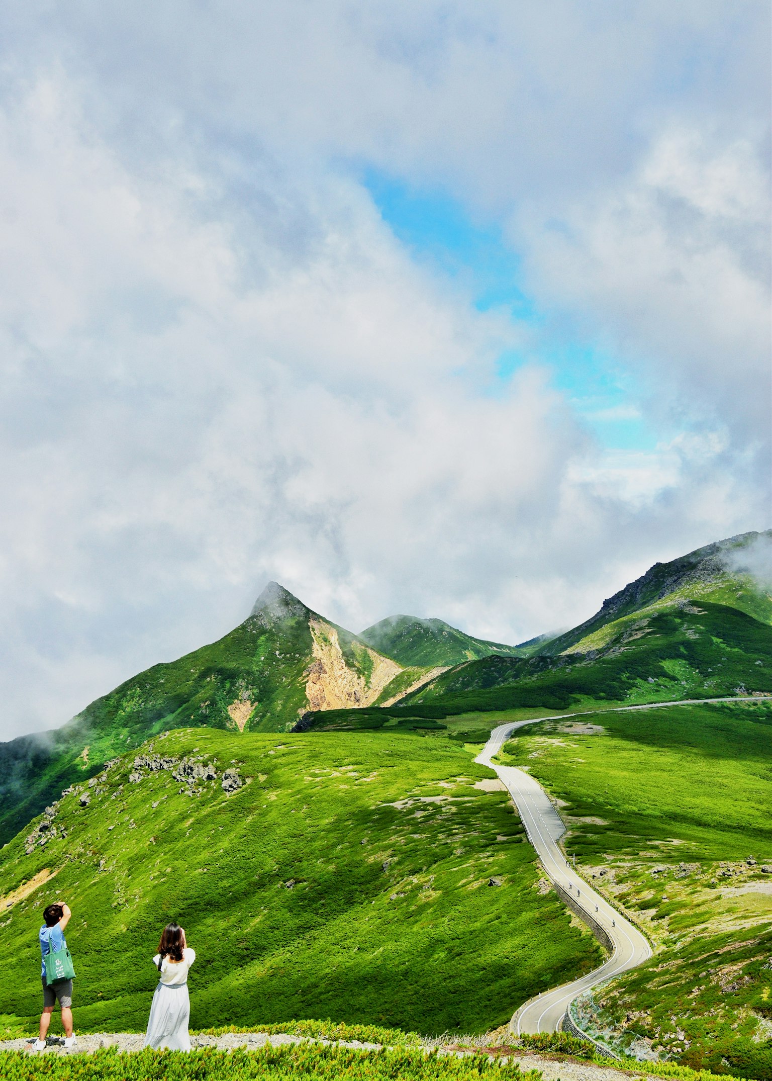 緑豊かな山々と青空を背景にした二人の観光客