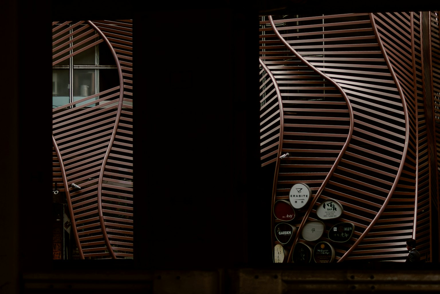 Vista a través de una ventana que muestra un diseño de listones de madera curvos y medidores visibles