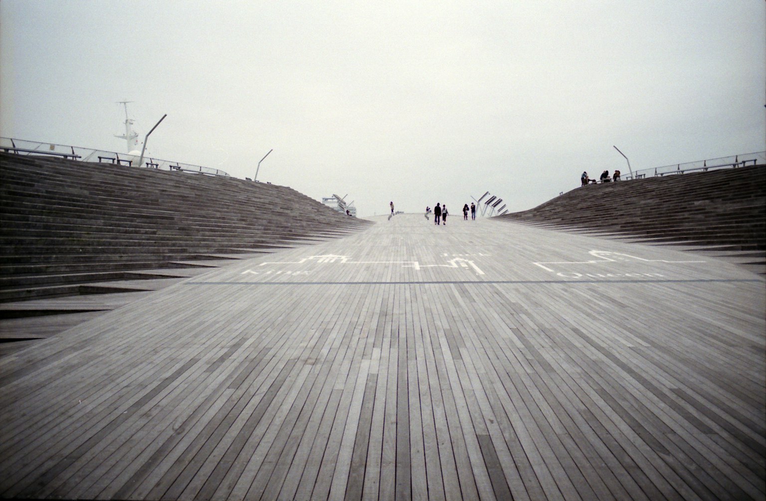 Wide wooden pathway under a cloudy sky with people walking