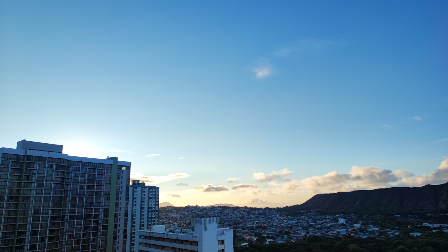 Bầu trời xanh với mây có tòa nhà cao và cảnh núi