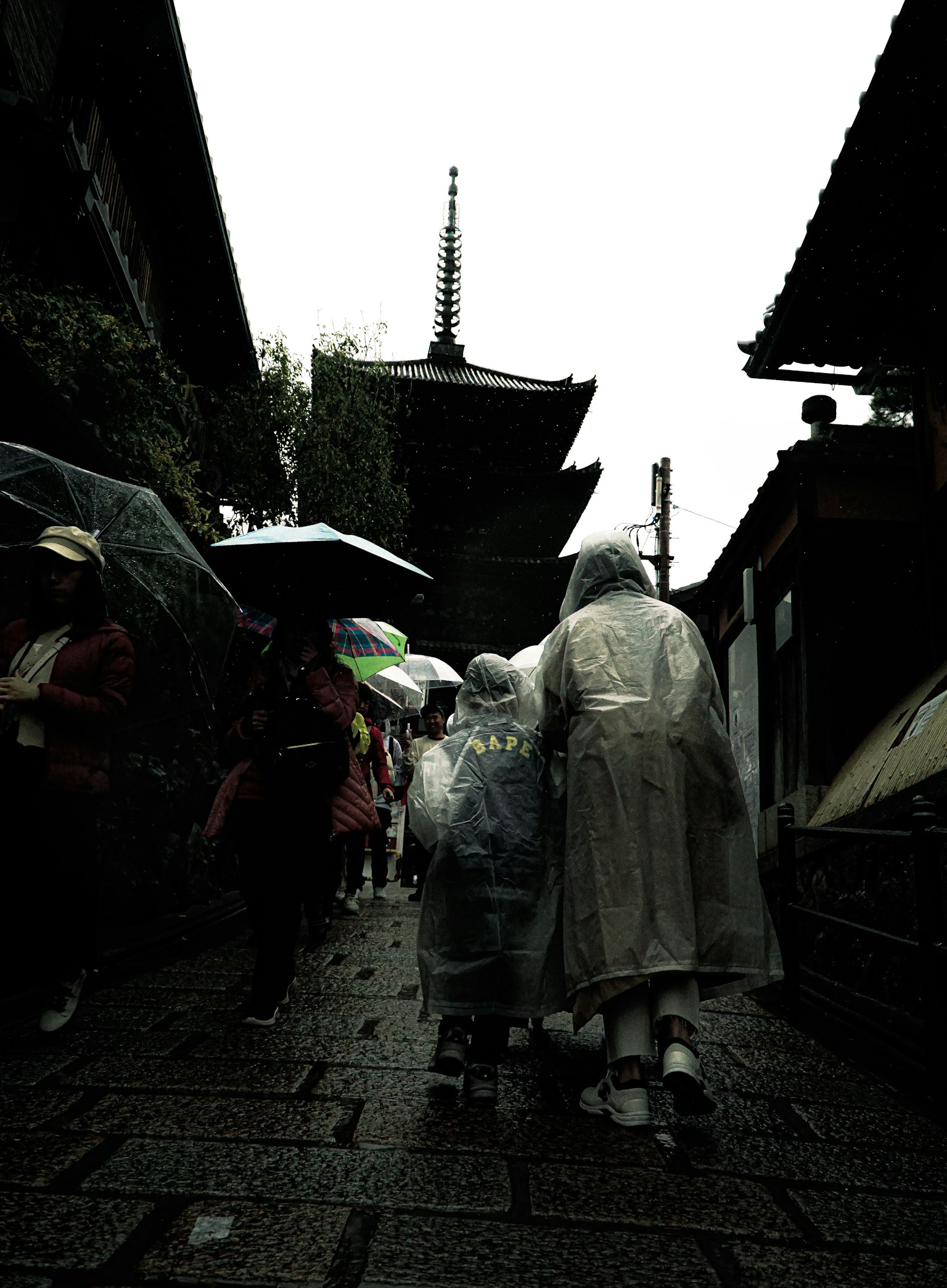 Personas caminando bajo la lluvia con edificios tradicionales de fondo