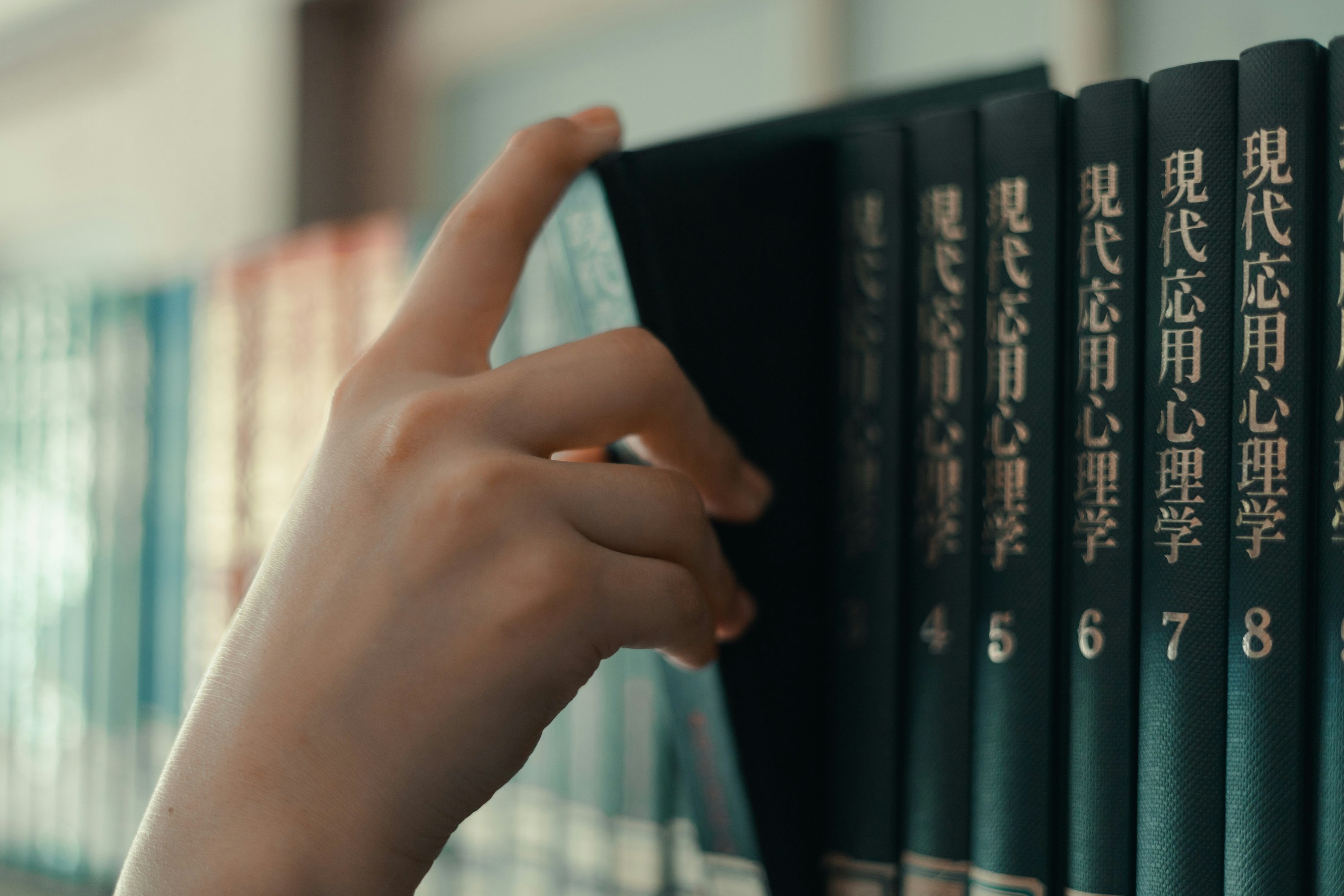 hands reaching for books on a bookshelf