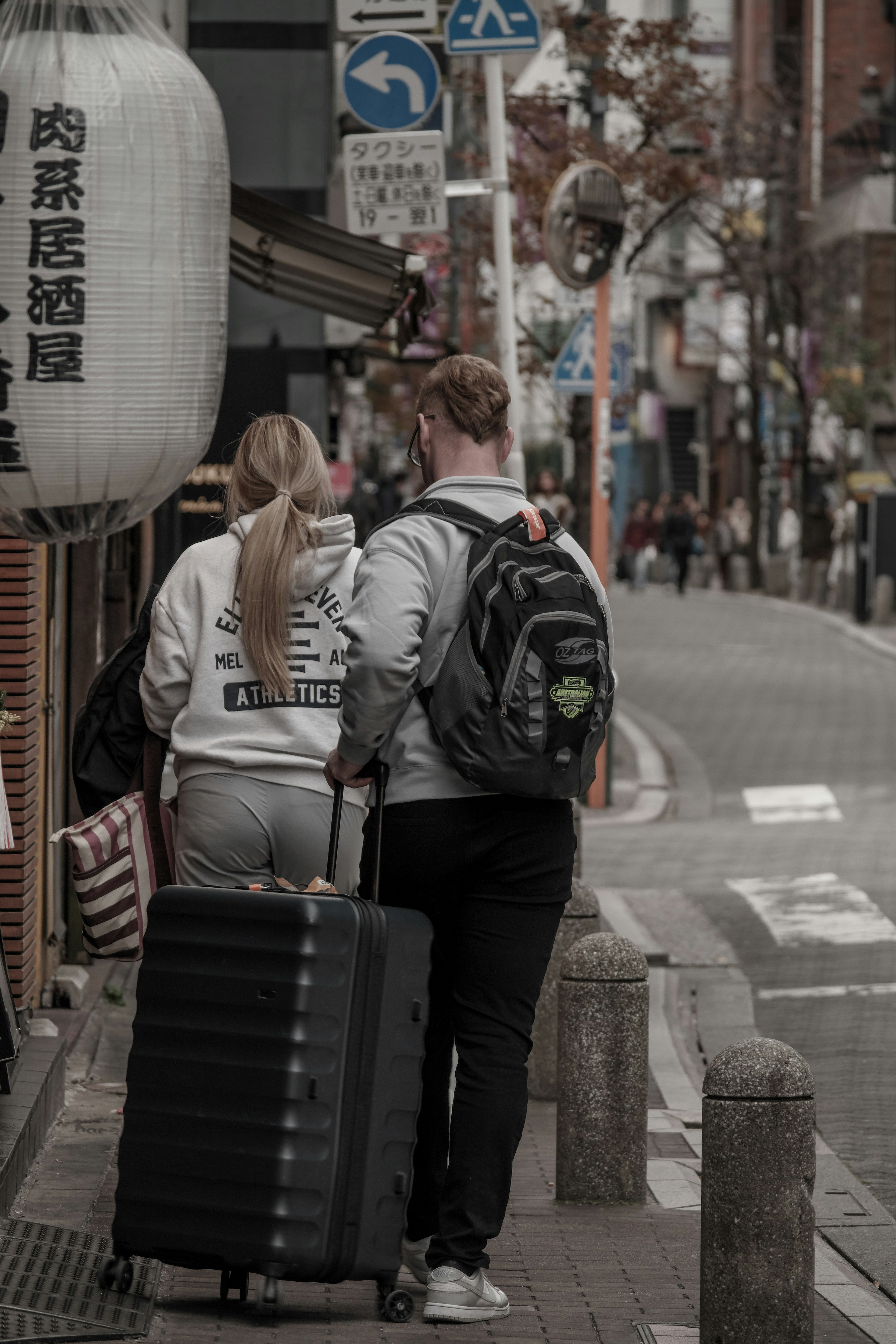 Tourists with suitcases along a narrow shopping alley storefront
