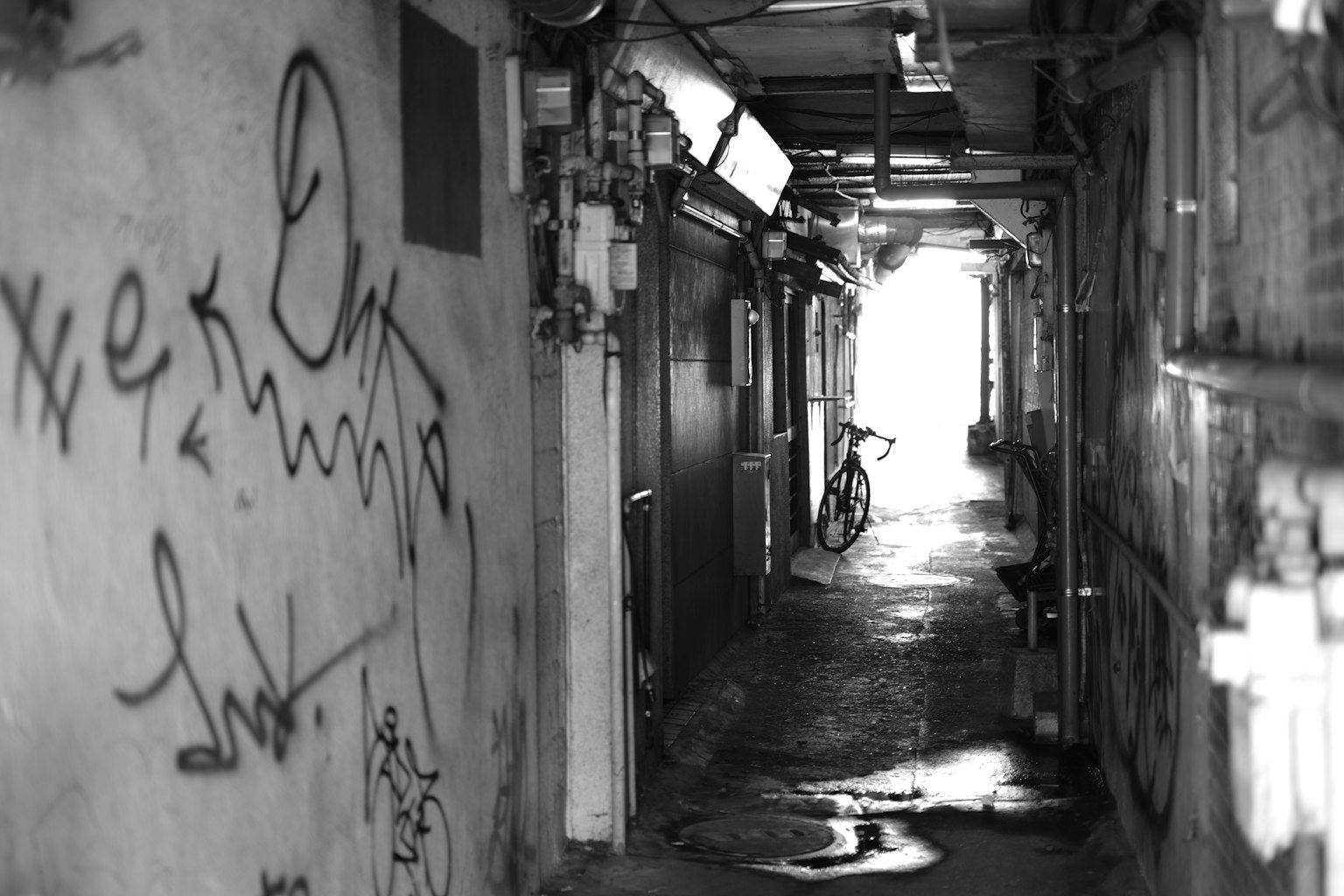 Lorong gelap dengan grafiti di dinding dan pintu keluar terang di kejauhan