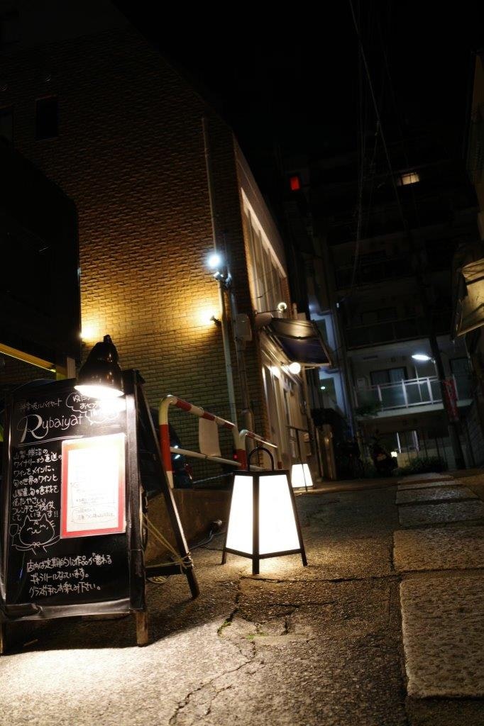 夜の路地に並ぶ看板と提灯のある小さな店先