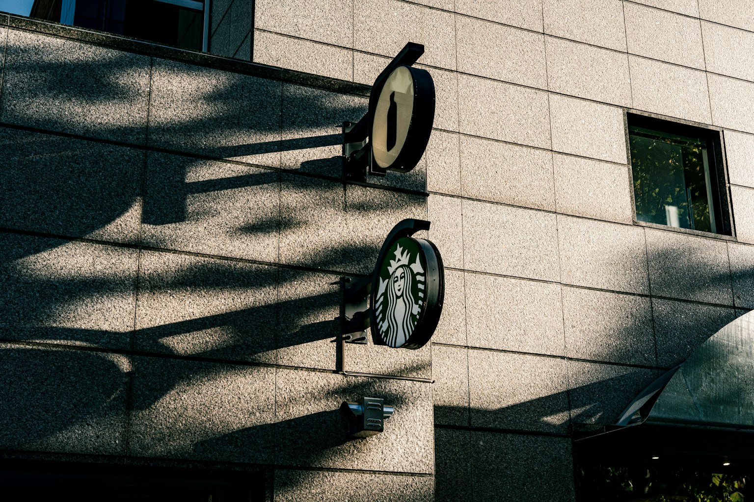 Starbucks-Logo und Schatten an einer Gebäudewand
