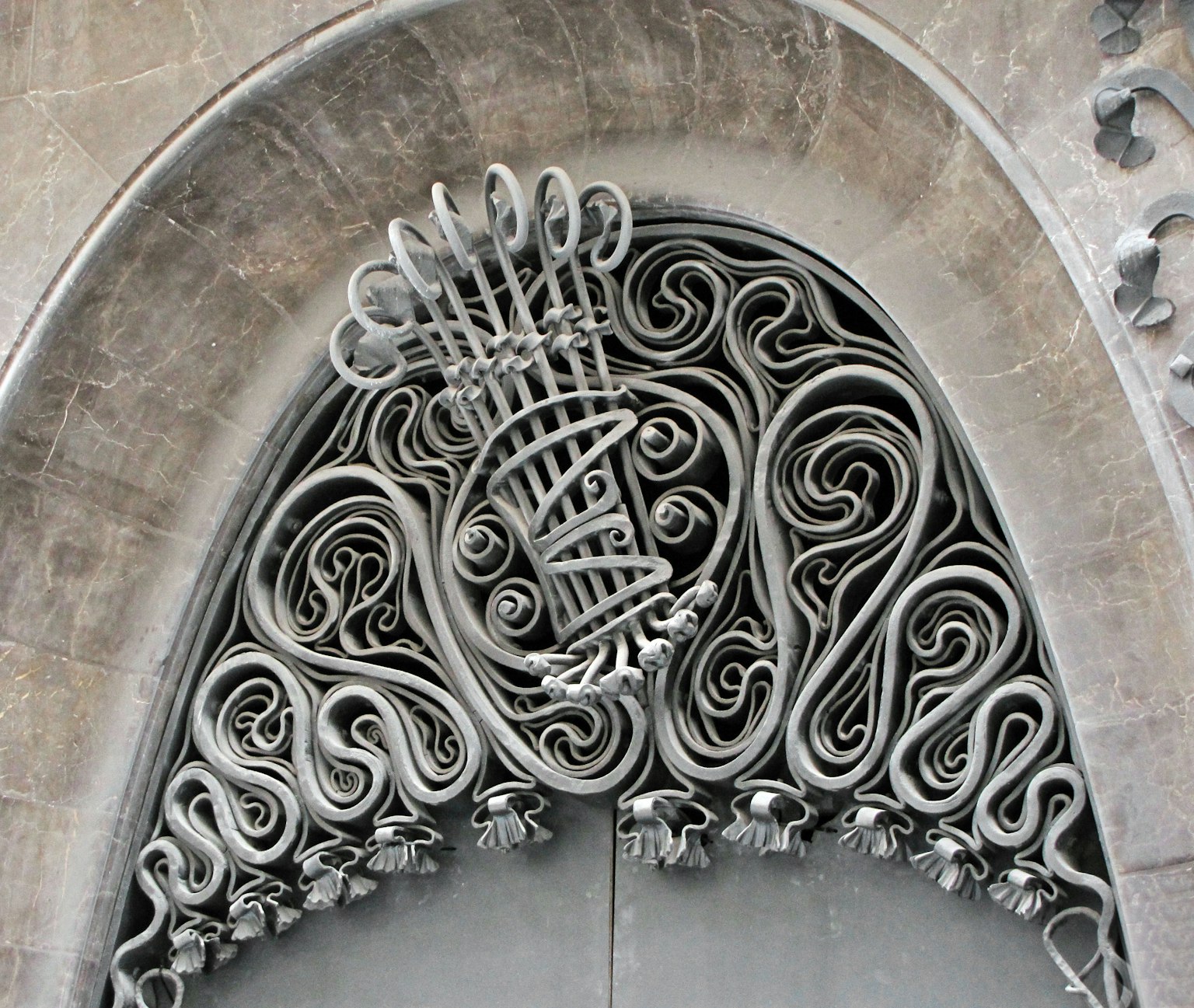 Diseño intrincado de metal en la parte superior de una puerta arqueada