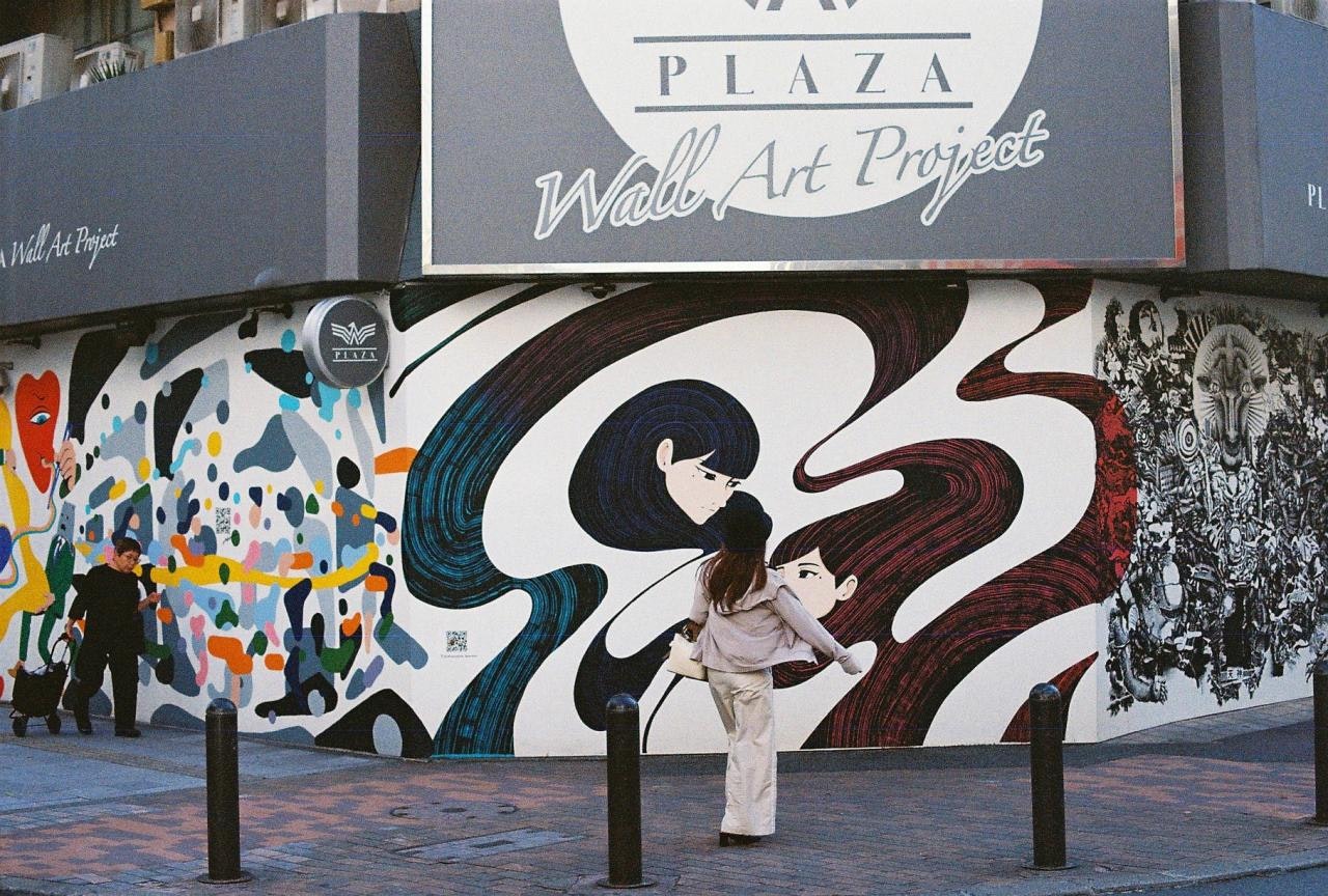 mur extérieur avec fresque et panneau, parent et enfant marchant devant