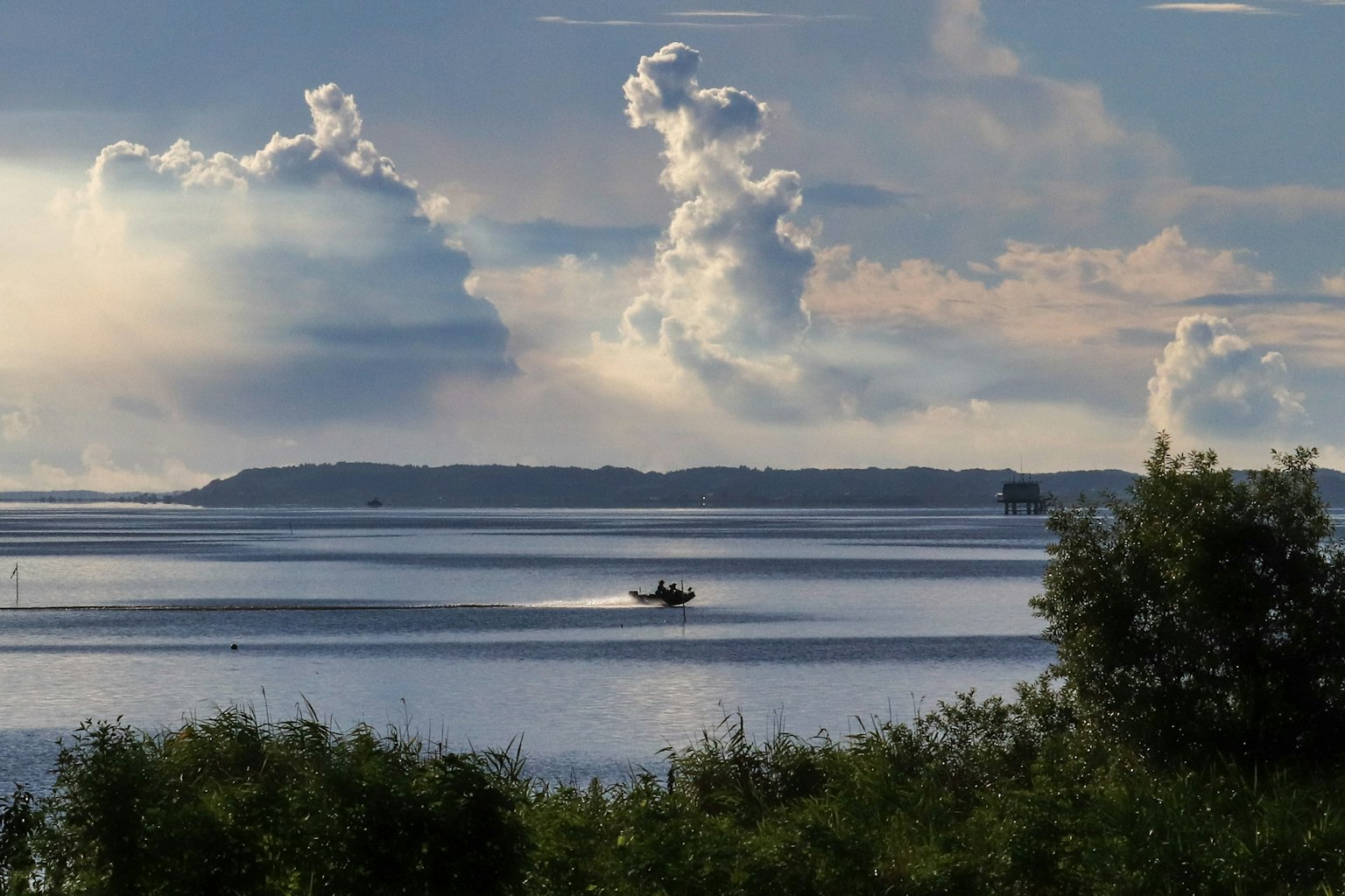 A small boat on a lake with clouds in the sky