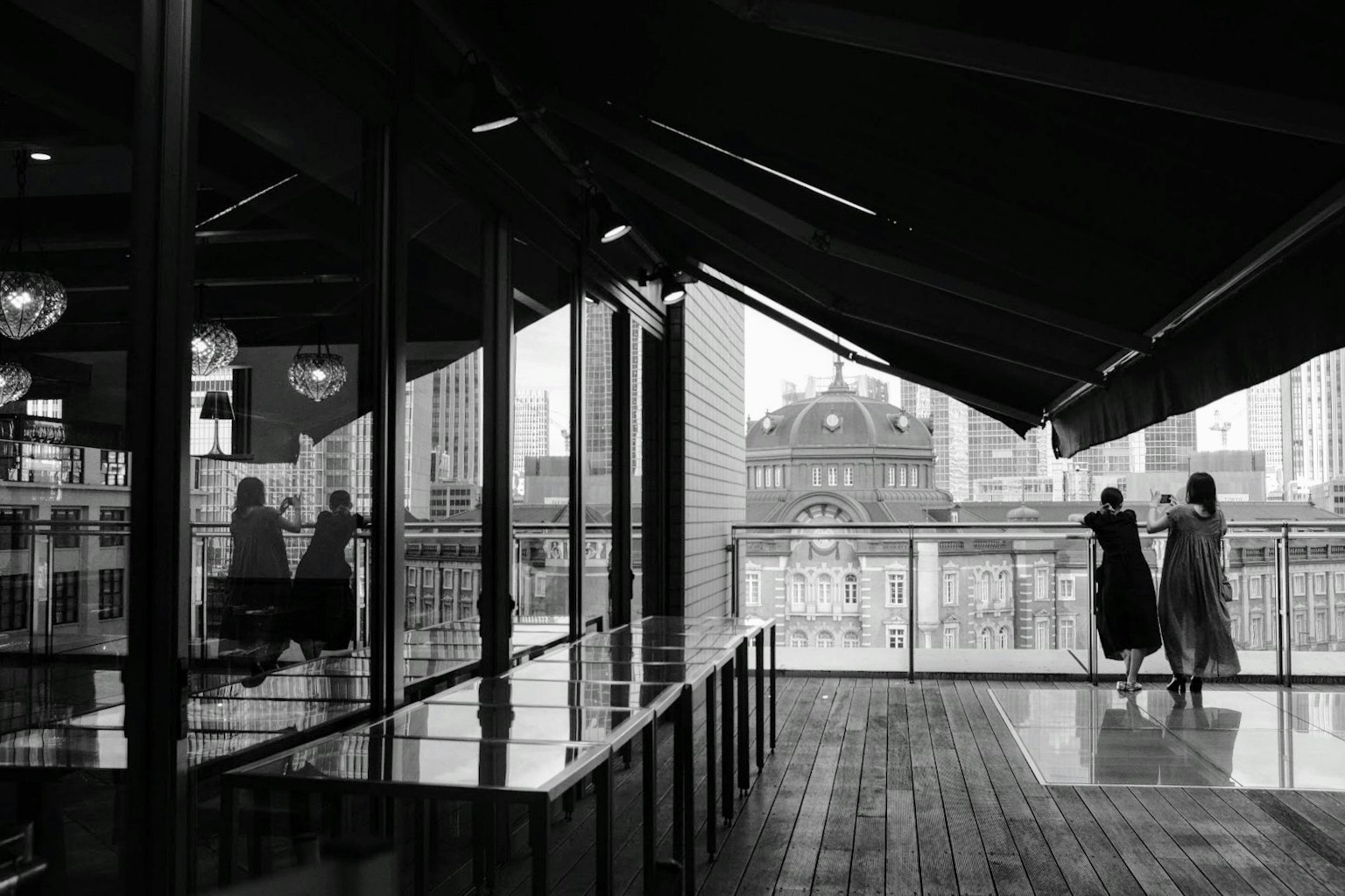 Silhouettes of two women overlooking the city from a modern balcony