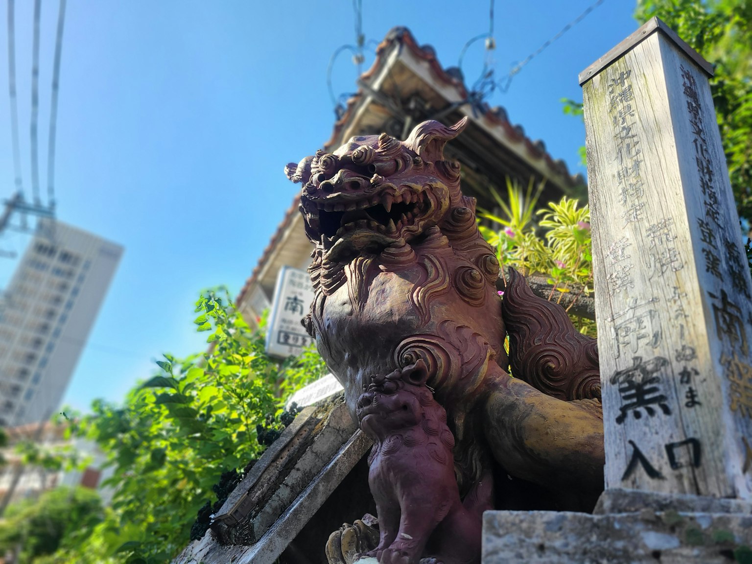 Statua del leone di Okinawa con un vecchio edificio sullo sfondo