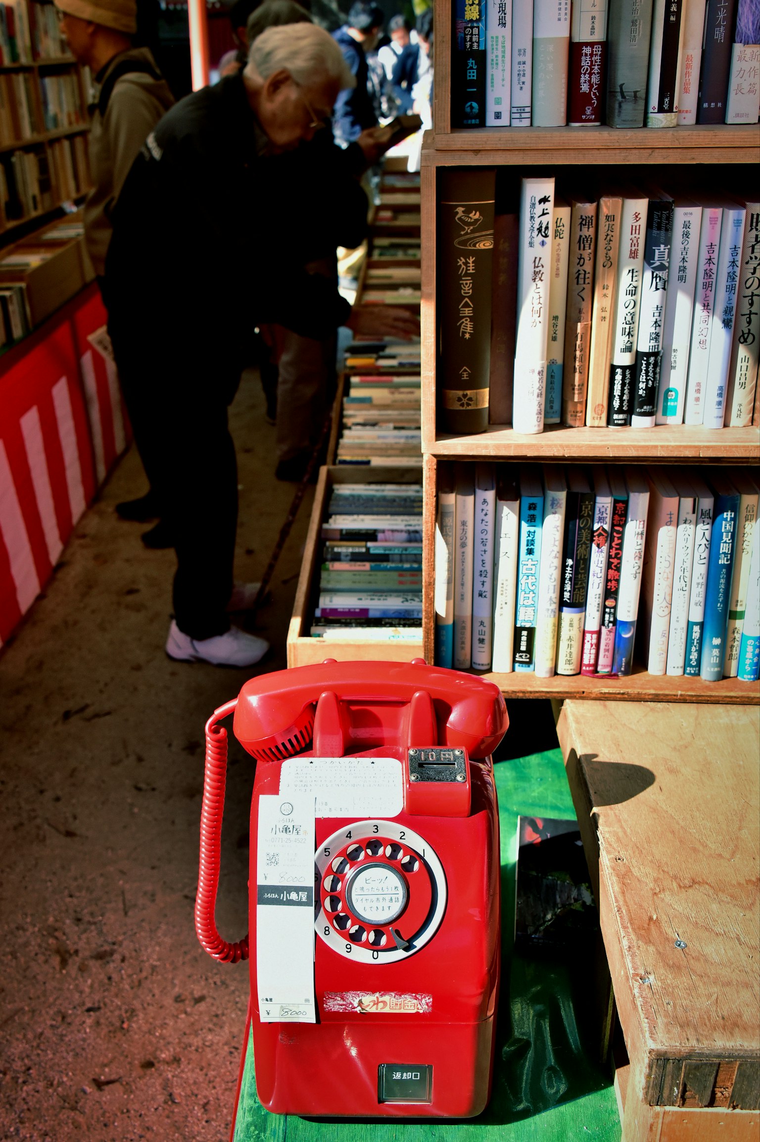 赤い電話機と本棚が並ぶ古本屋の風景