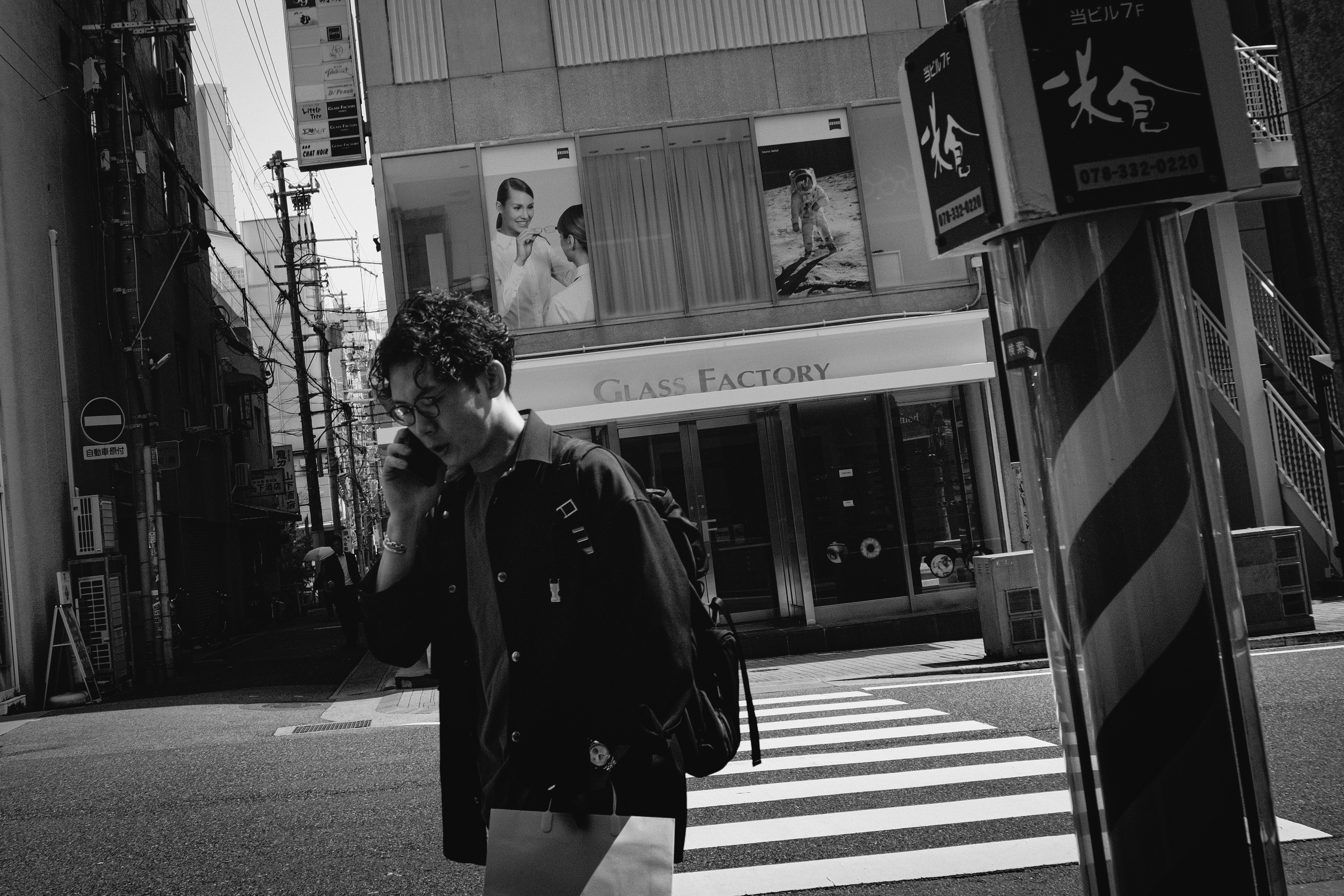 路地の横断歩道を歩く人物と看板のある街並み