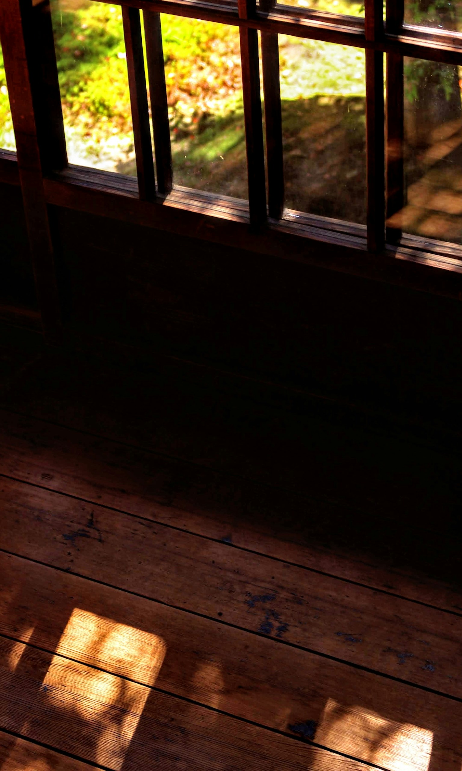 Wooden floor with natural light casting shadows from the window