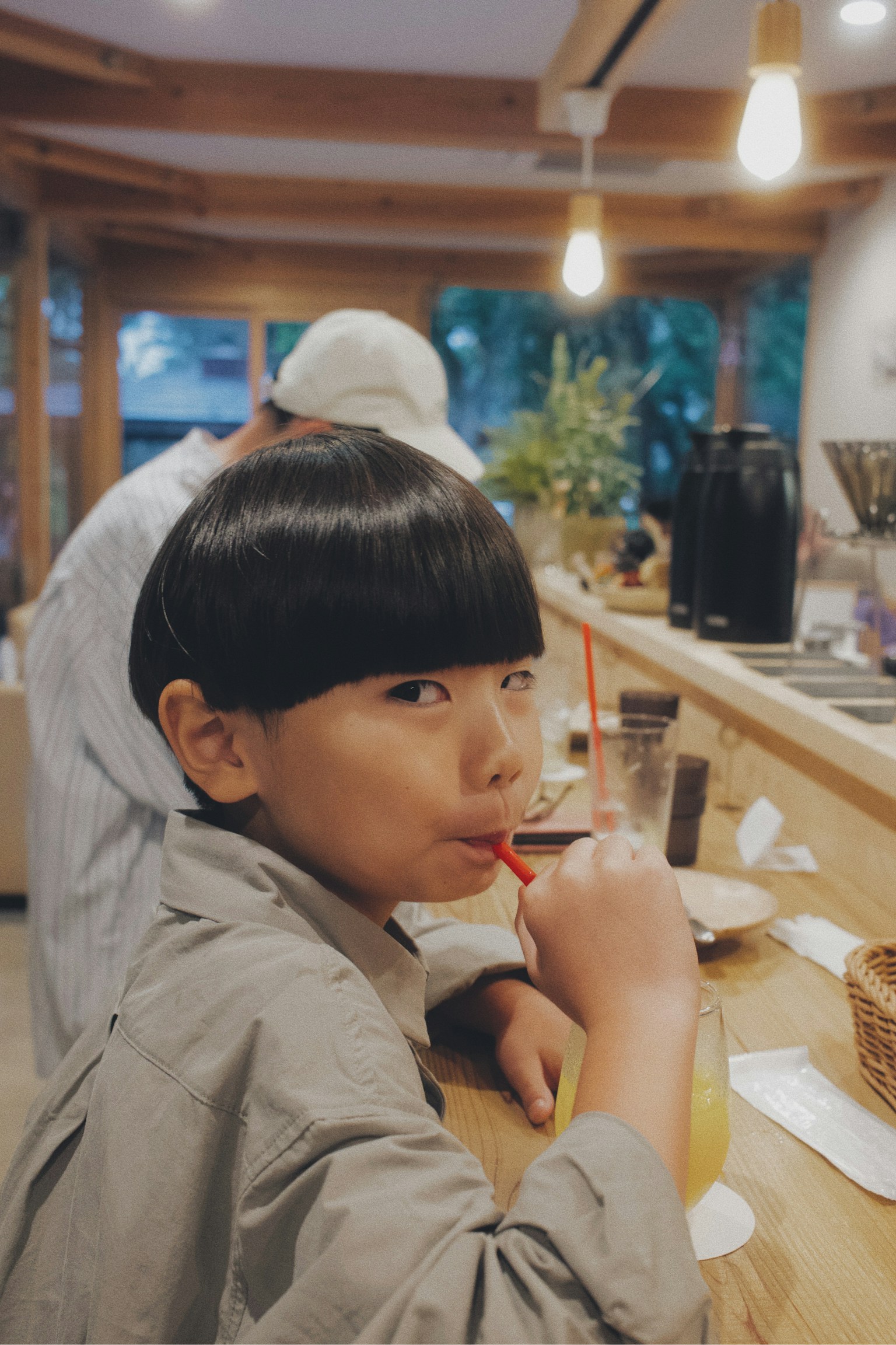 Profile of a boy sipping a drink in a cafe with warm interior lighting