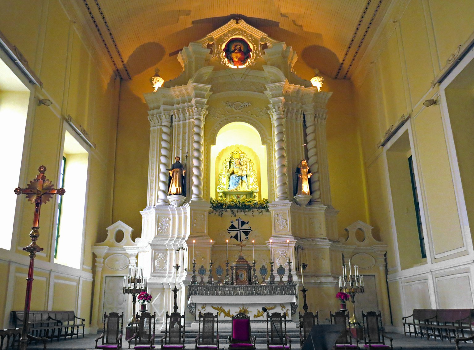 Interior de una hermosa iglesia con paredes amarillas altar blanco y estatuas
