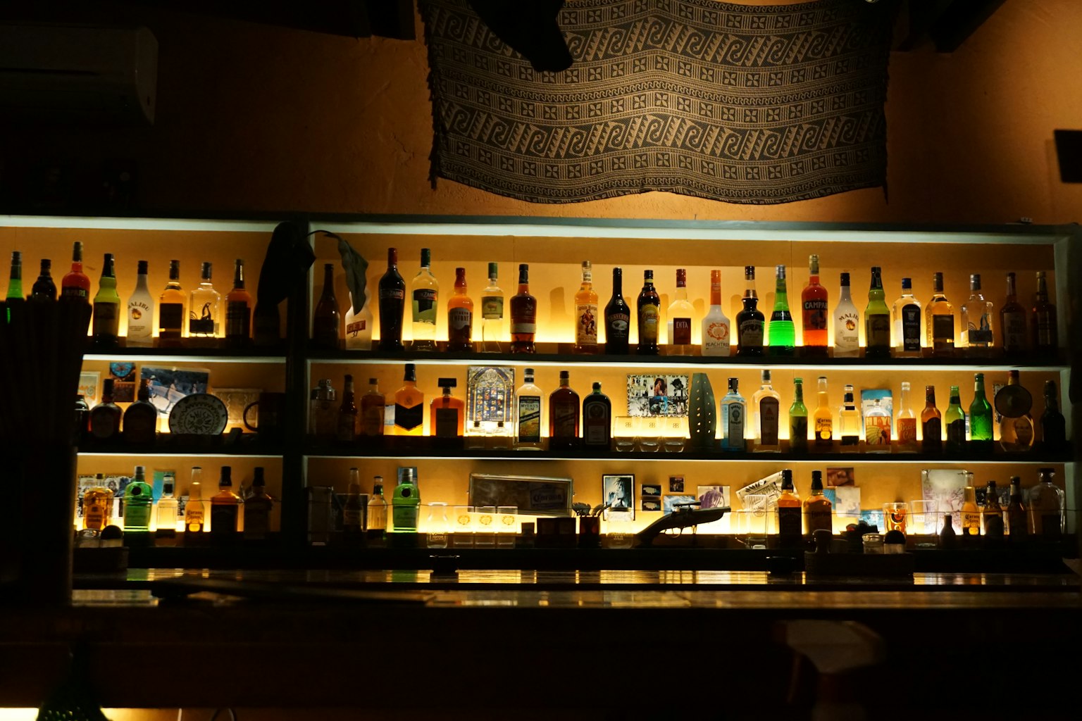 Botellas iluminadas dispuestas en estanterías en un bar con poca luz