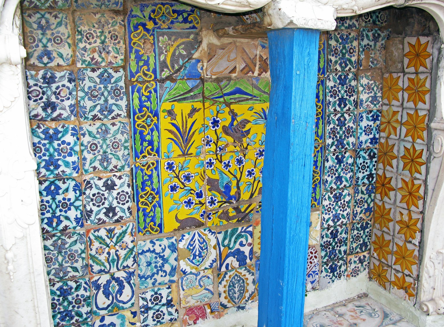 Mur carrelé coloré avec des motifs complexes et une colonne bleue brillante