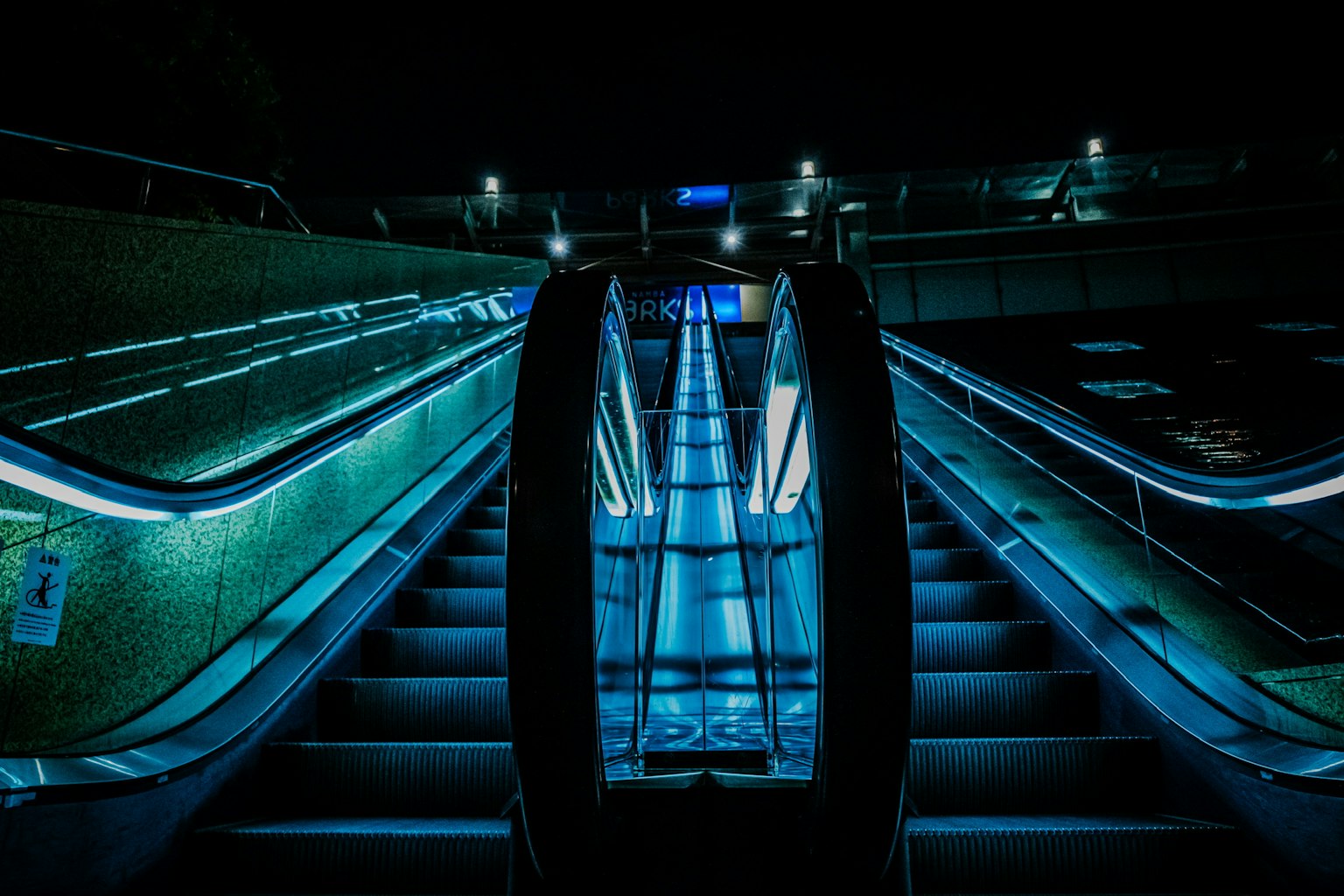 Image d'un escalator illuminé par une lumière bleue dans un espace sombre