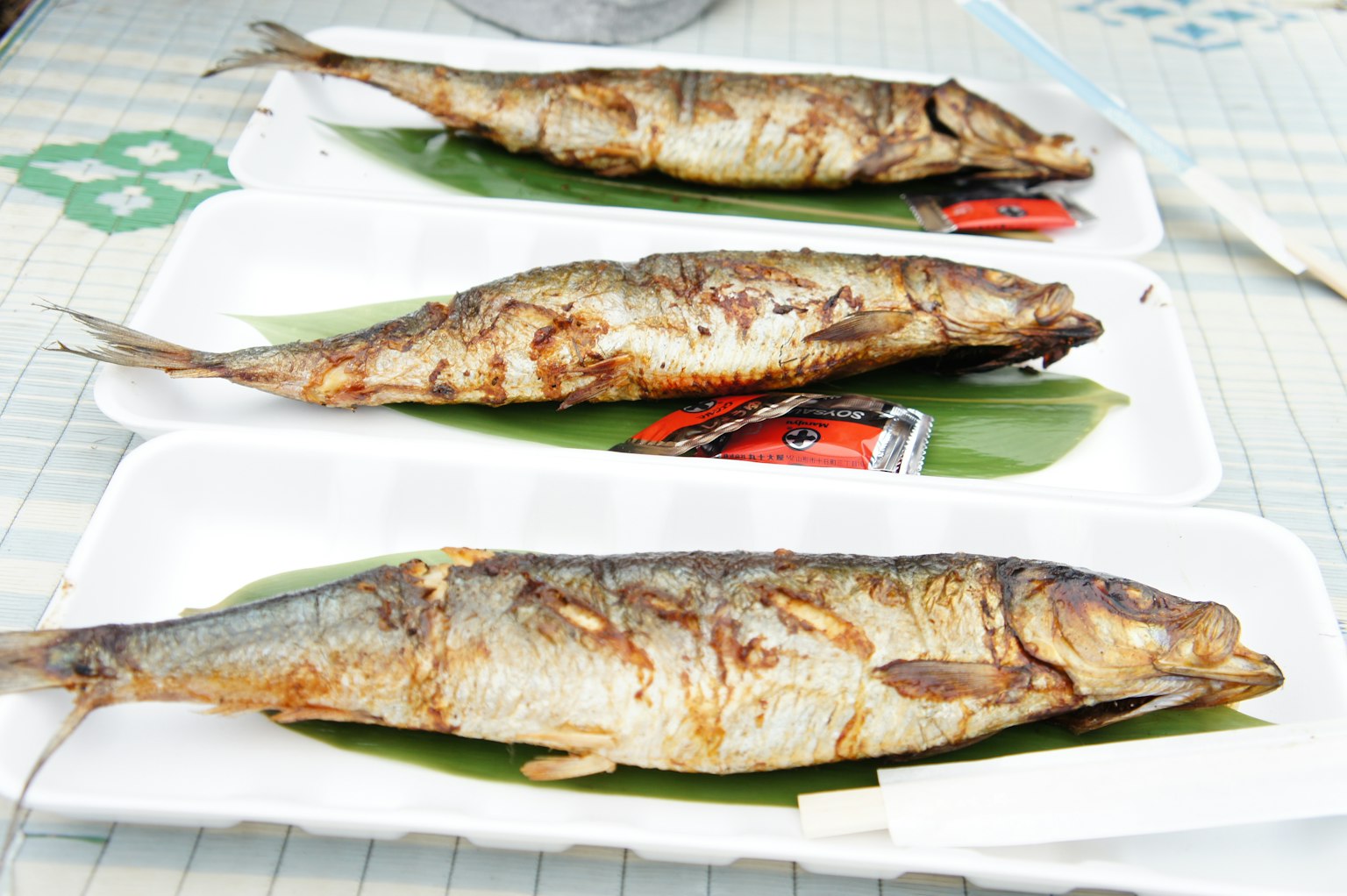 Ikan bakar disajikan di piring yang dihiasi daun pisang